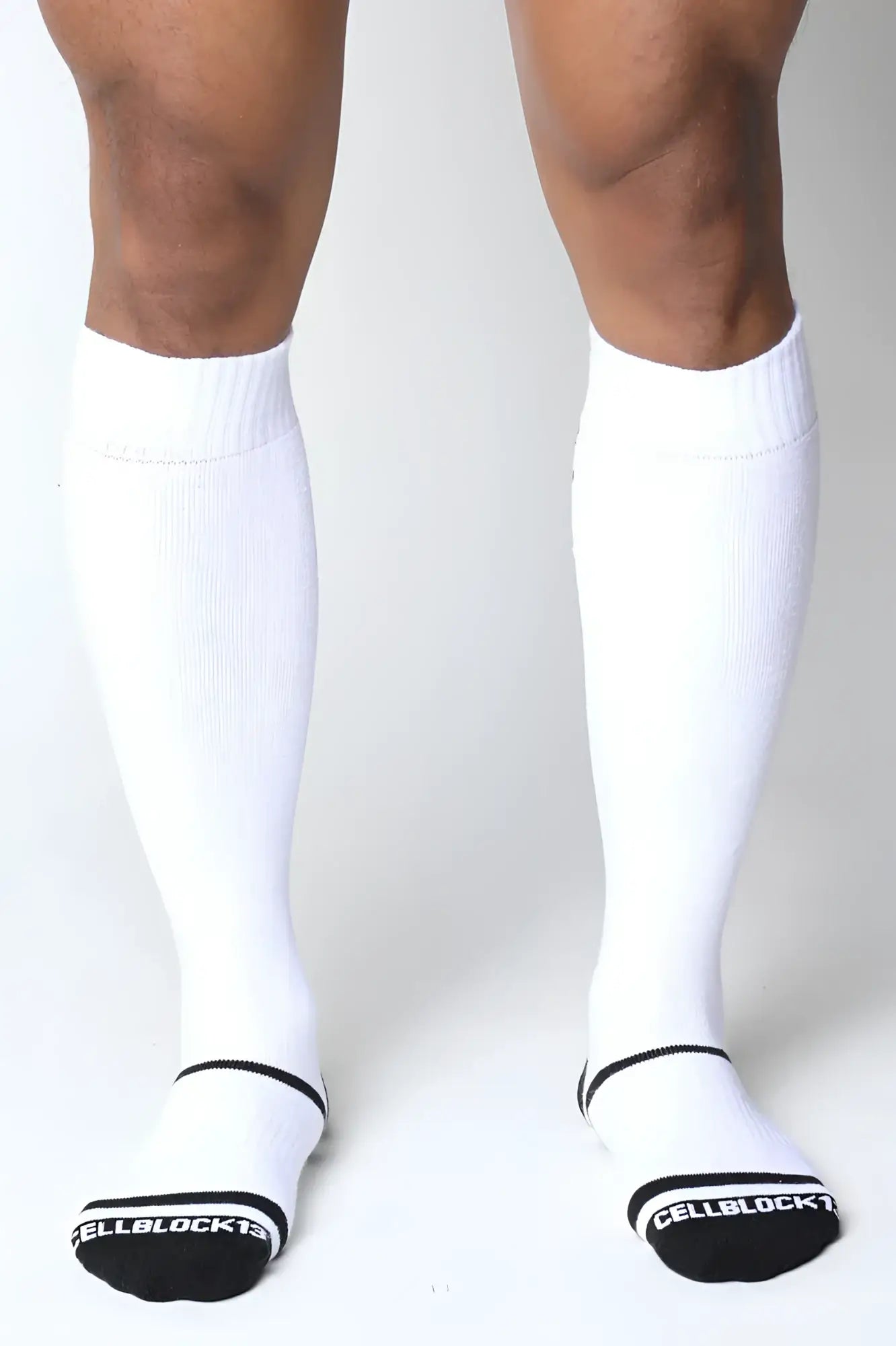White knee high socks with black trim ribbed texture and cellblock 13 branding on the heel showing back view