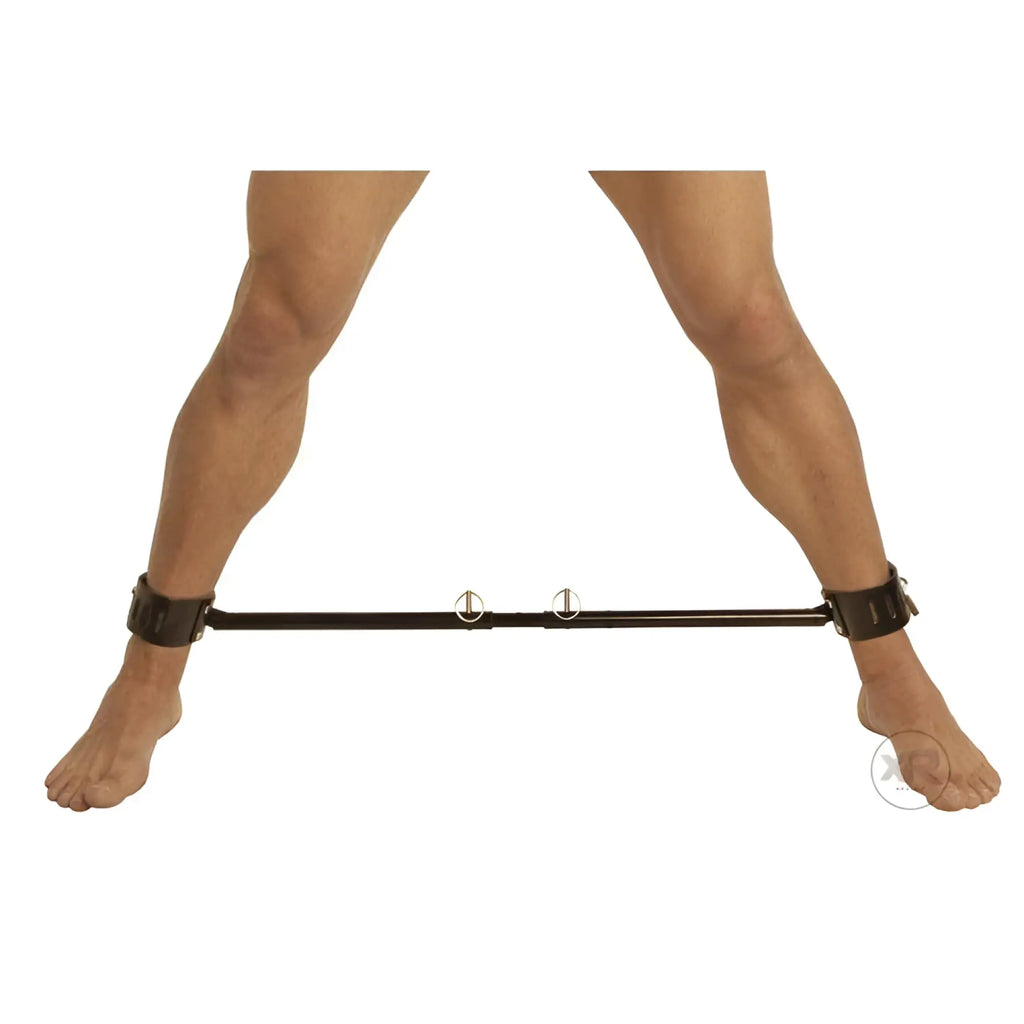 Kink Industries adjustable black spreader bar with matching ankle cuffs attached to a person’s legs.