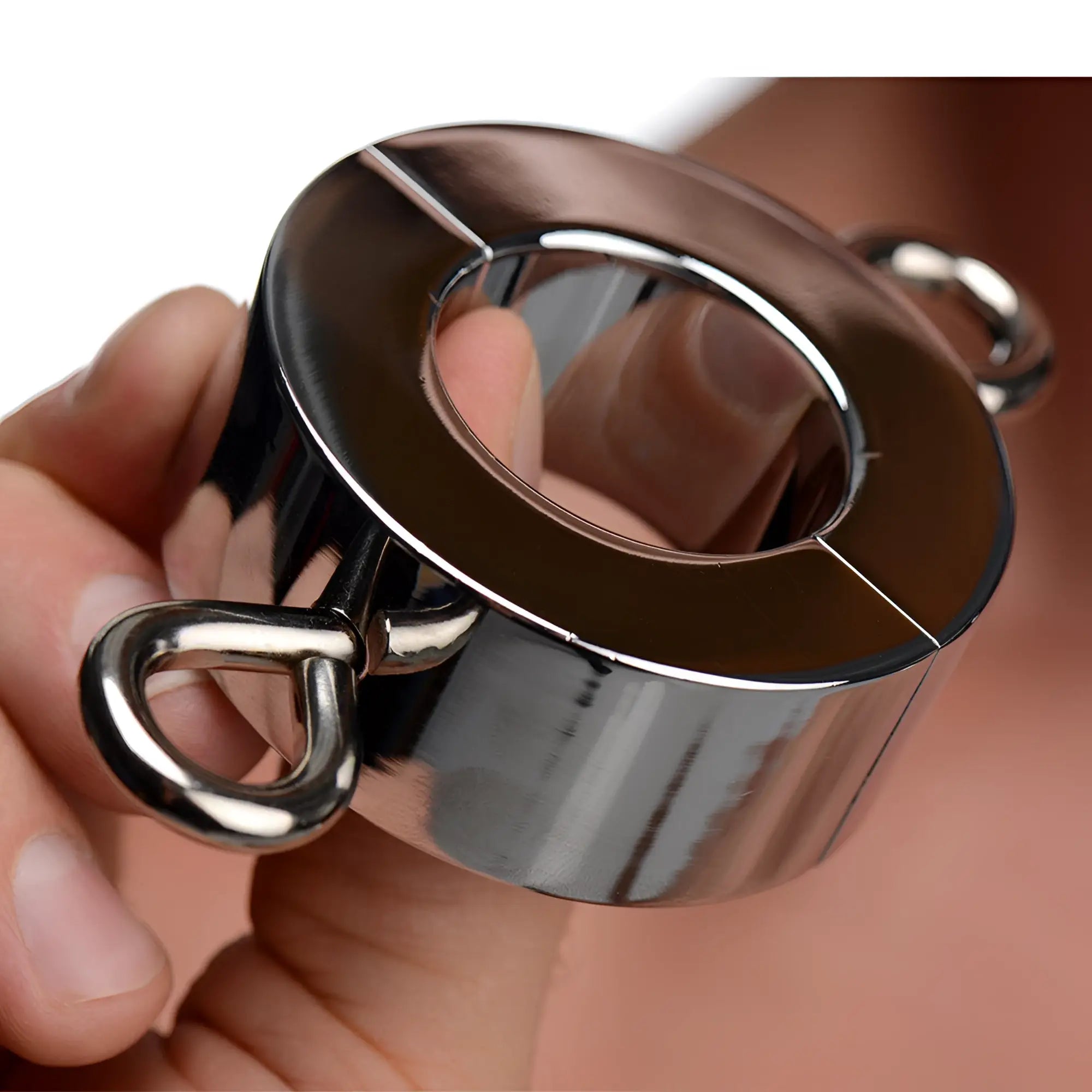 A chrome Kink Industries ball stretcher weight being held, featuring a two-piece hinged design with side ring loops.