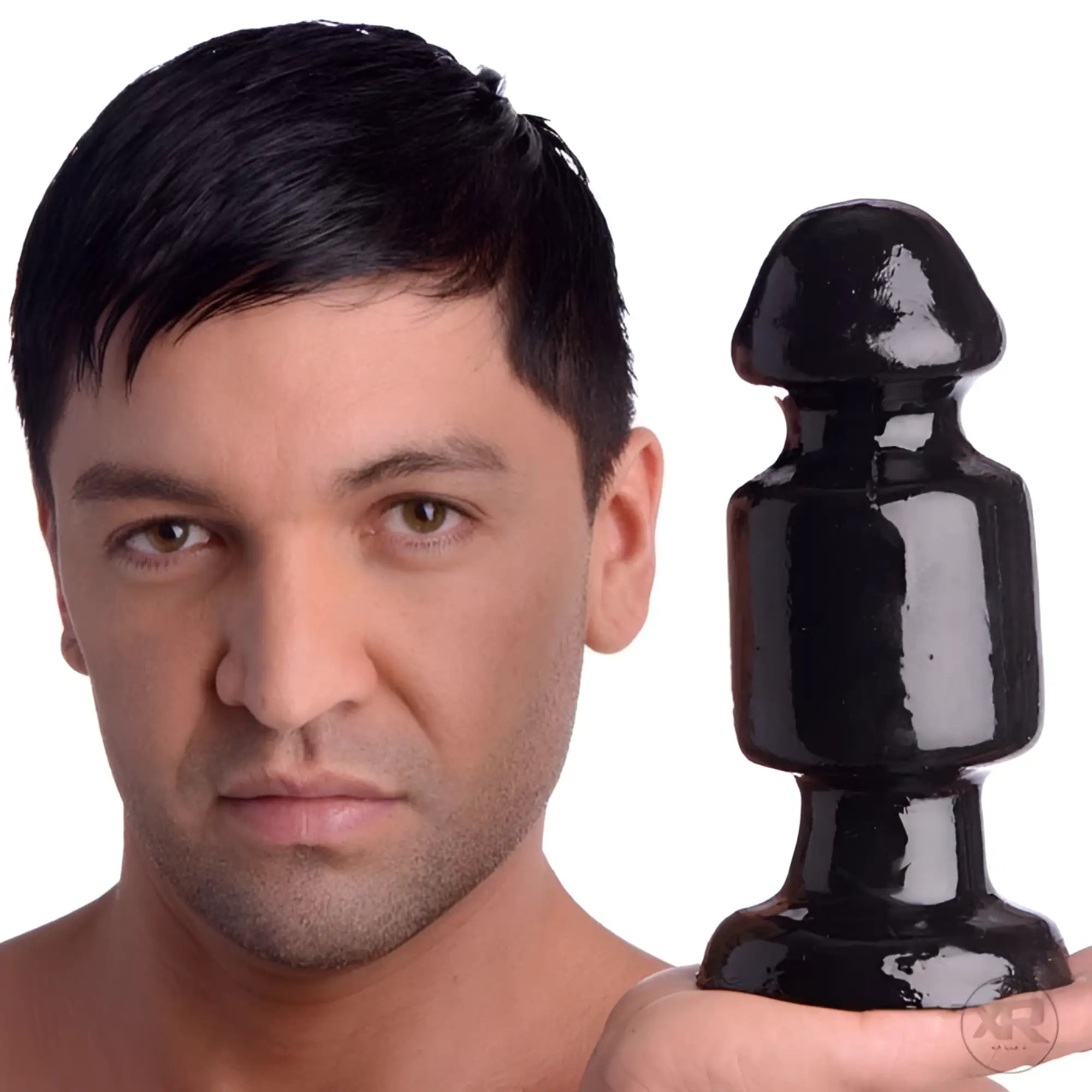 A man holds a large, glossy black Kink Industries The Keg butt plug, featuring a cylindrical body and rounded head.