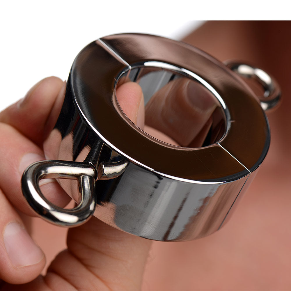 A chrome Kink Industries ball stretcher weight being held, featuring a two-piece hinged design with side ring loops.
