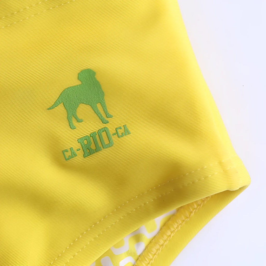 Close-up of a lemonade yellow CA-RIO-CA swimming sunga featuring a green dog logo and brand embroidery.