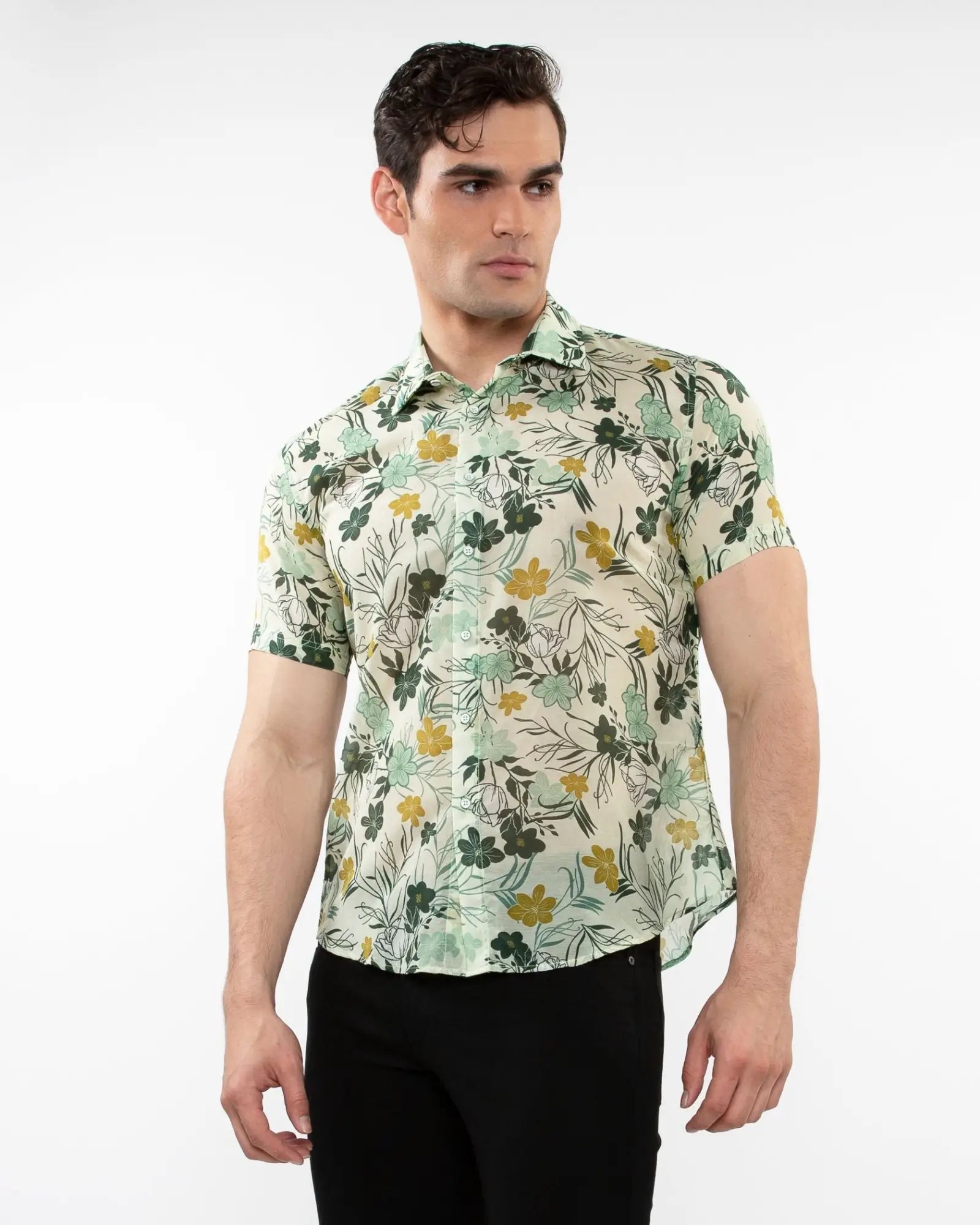 A man wearing a lightweight cotton silk short-sleeved shirt with green and yellow floral pattern on off-white background