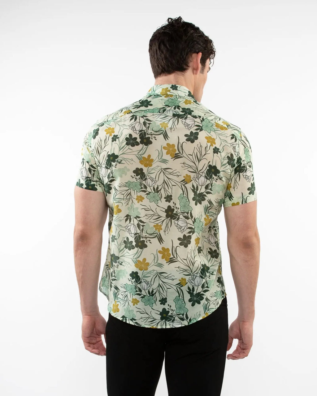 A man wearing a lightweight cotton silk short-sleeved shirt with a green yellow floral pattern on off-white background