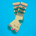 Cream-colored crew socks with teal and pink stripes featuring black text i like dogs more than people for casual wear