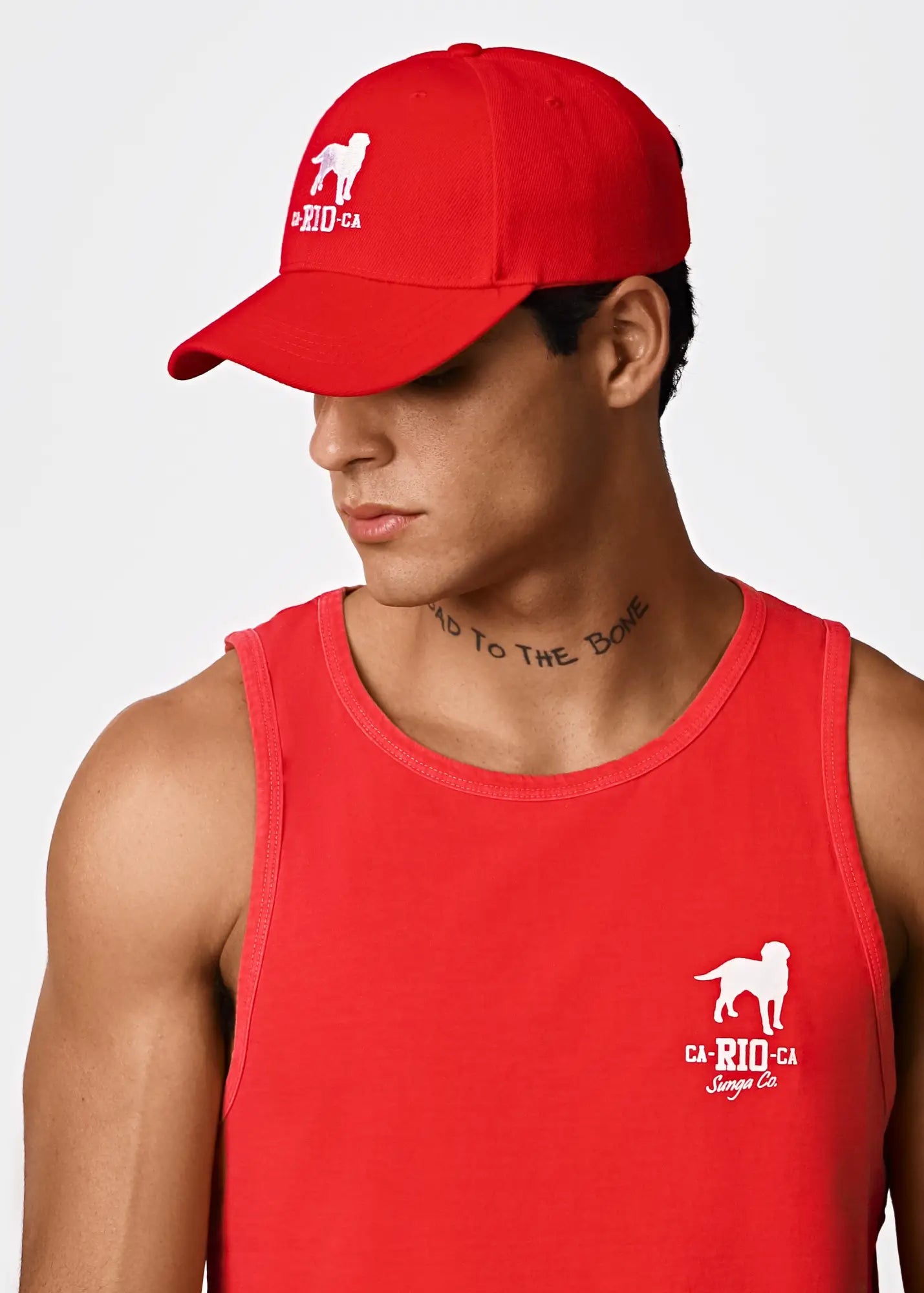 Red baseball cap with white embroidered dog logo and ca-rio-ca text featured with men’s logotipo red tank top