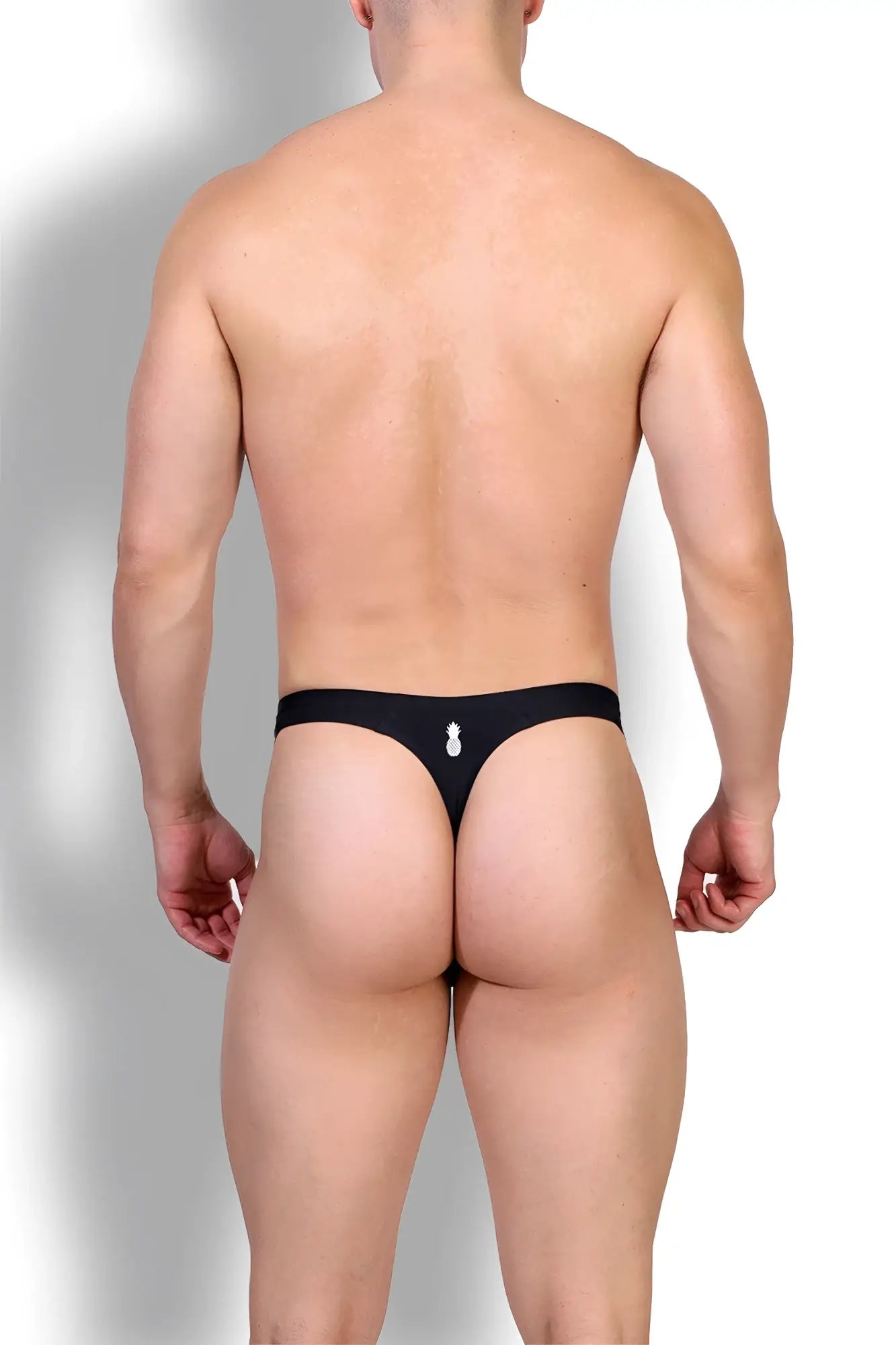 Black seamless thong in midnight black with a small white pineapple emblem on the back center
