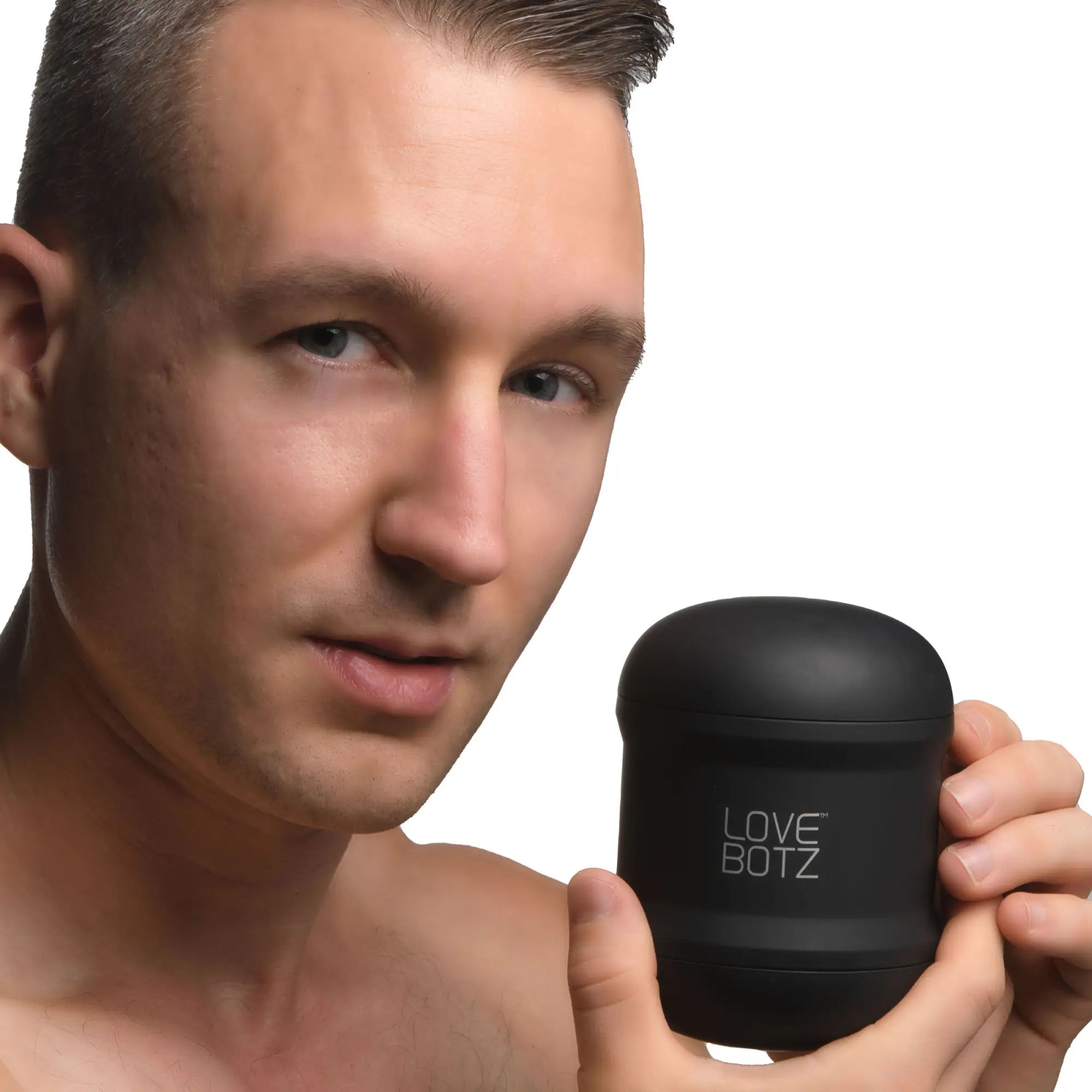 A man holding a matte black, cylindrical LoveBotz 10X Cyber Stroke masturbator with the brand name printed on the side.