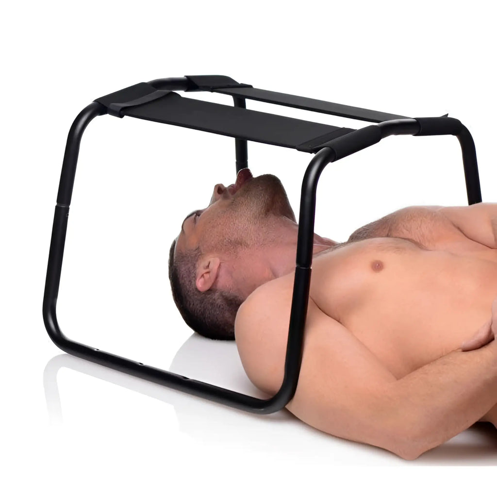LoveBotz Extreme Sex Stool: A black metal frame stool with a fabric seat positioned over a man lying on his back.