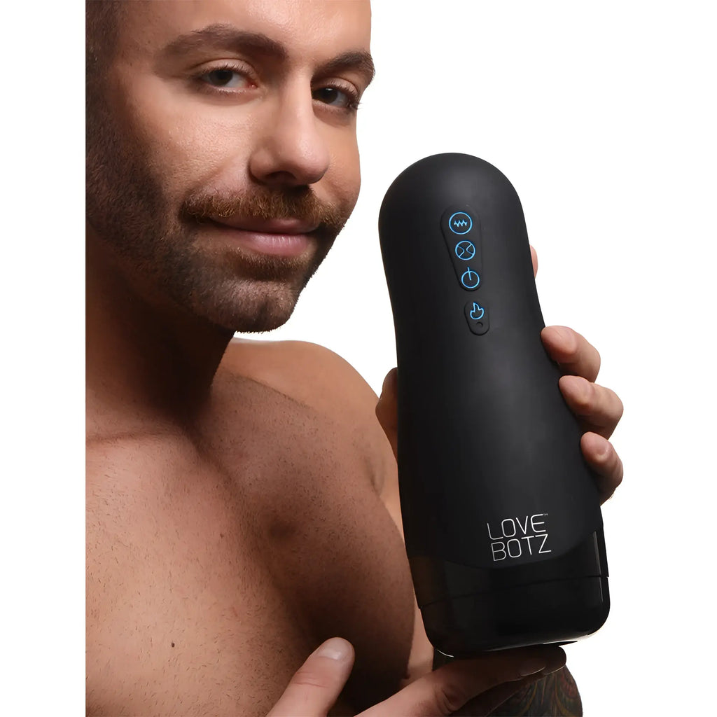 A man holds the black LoveBotz The Milker 15X Squeezing Masturbator, which features glowing blue control buttons.