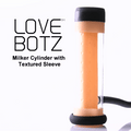 LoveBotz Milker Cylinder with a peach-colored, dimpled textured sleeve, black end caps, and a black hose attachment.