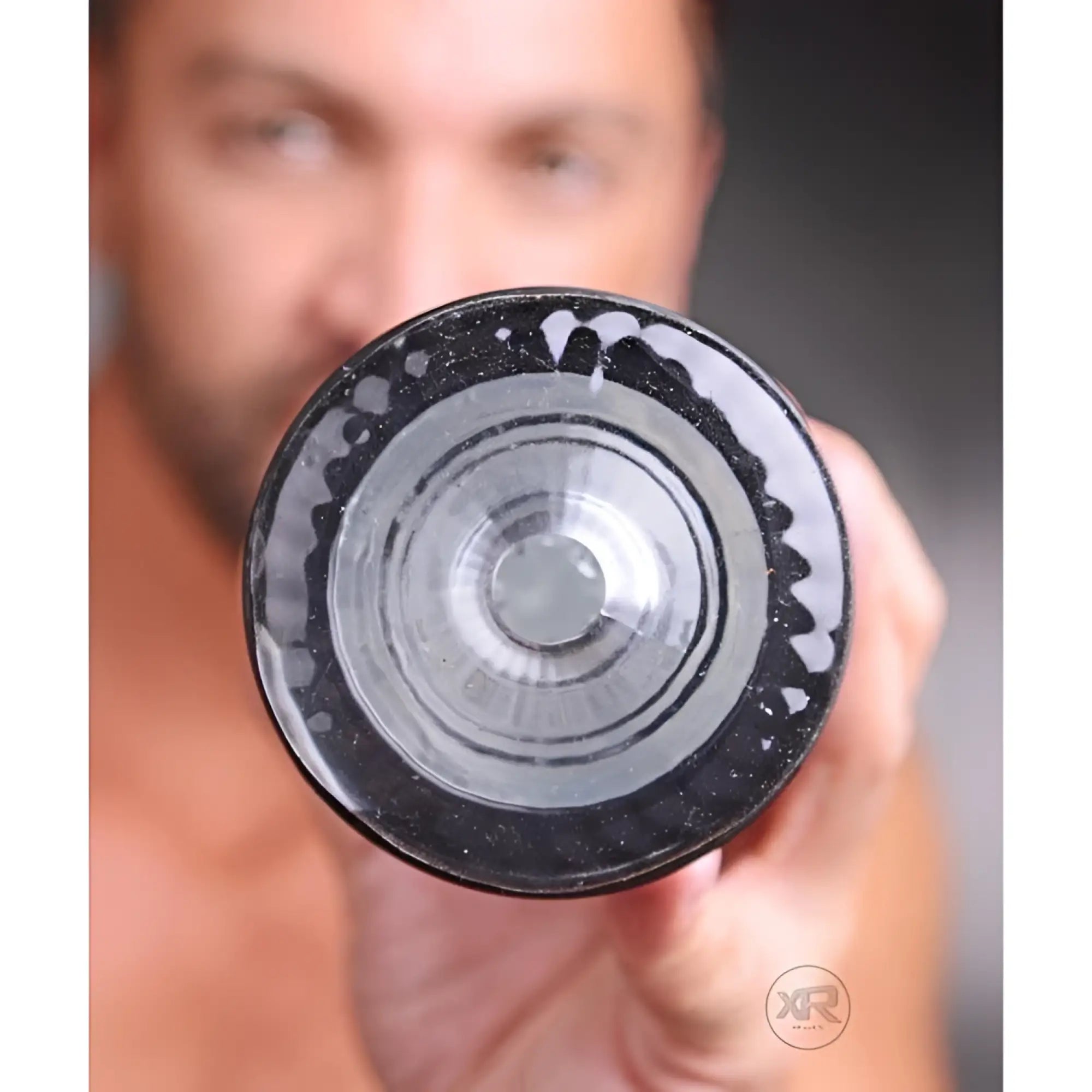 LoveBotz Strobe rechargeable stroker: A person holds the black, circular, textured opening of the device toward camera.