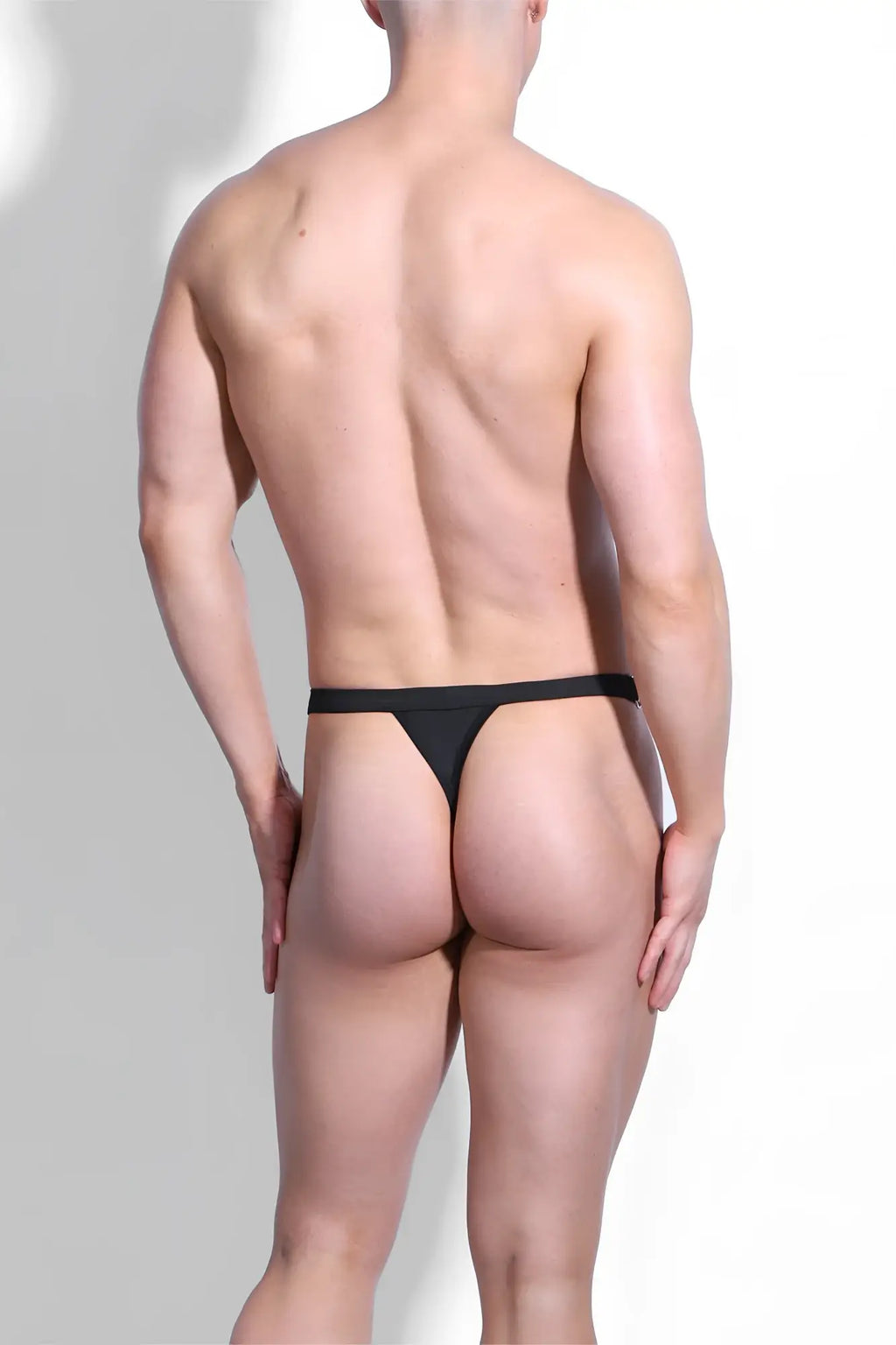 Black smooth form-fitting luster metal accent g-string swim thong in midnight black shown from the back side
