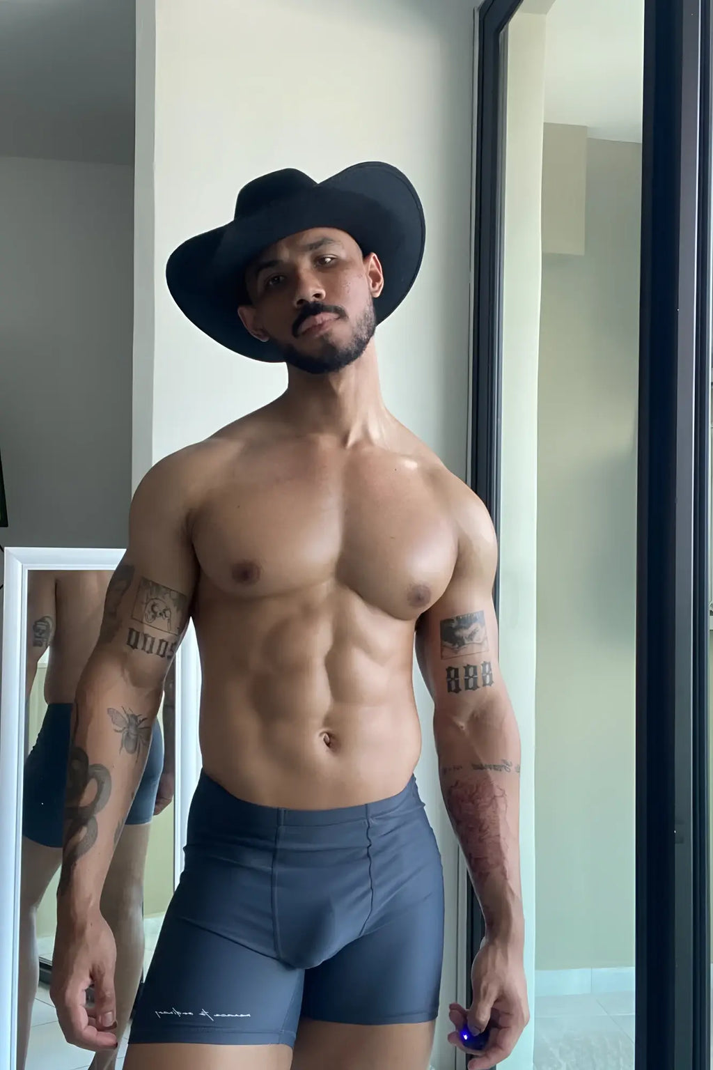 Black cowboy hat resting on lustrous scrunch-butt 4.5 bike shorts in graphite showing back side details