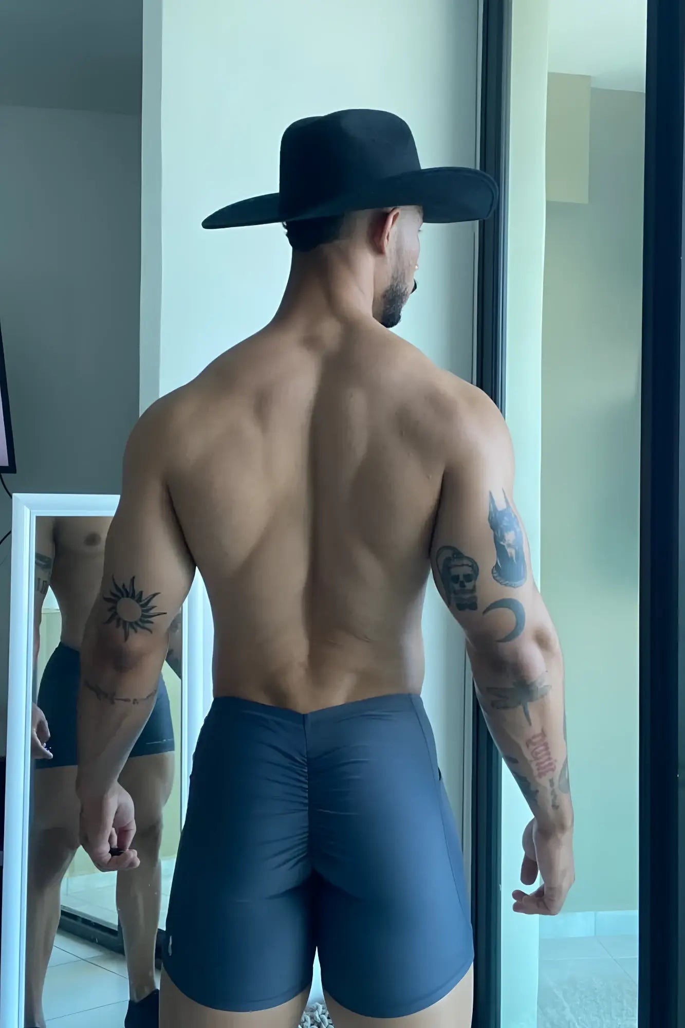 Black wide-brimmed cowboy hat paired with graphite lustrous scrunch-butt 4.5 inch bike shorts back view