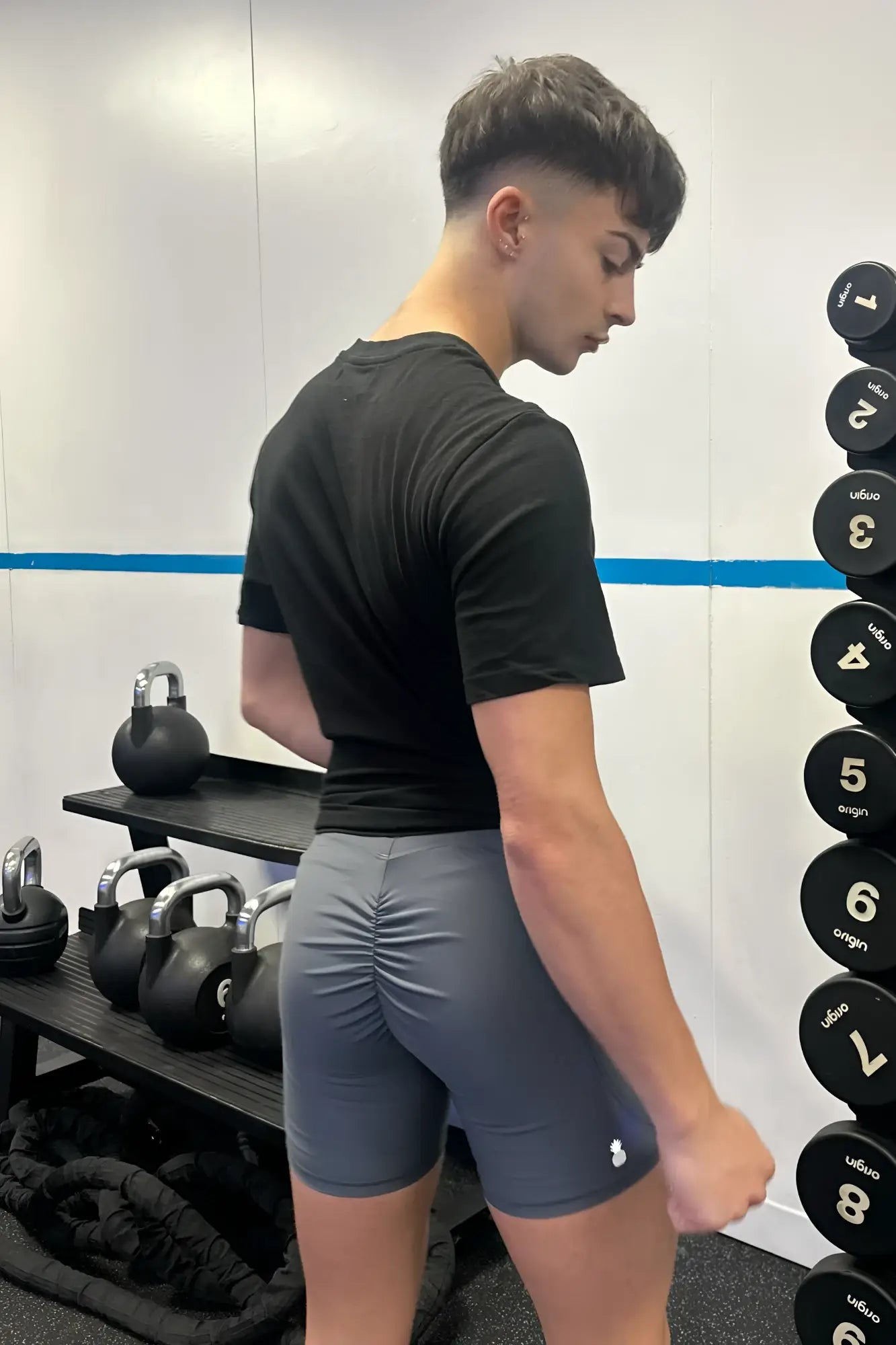 Back view of lustrous scrunch-butt 4.5 inch graphite bike shorts with ruched design and white logo on lower right leg