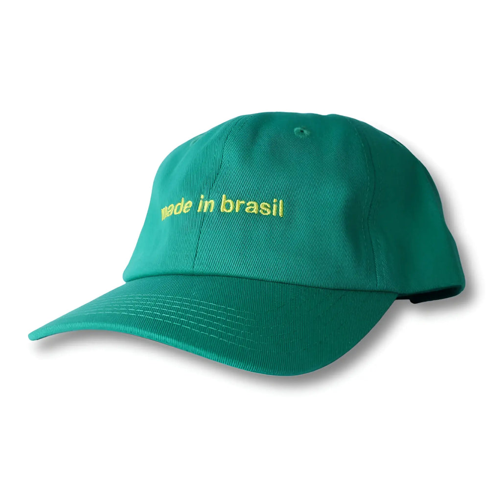 A teal green dad hat with yellow embroidered made in brazil text on the front, made in brasil collection