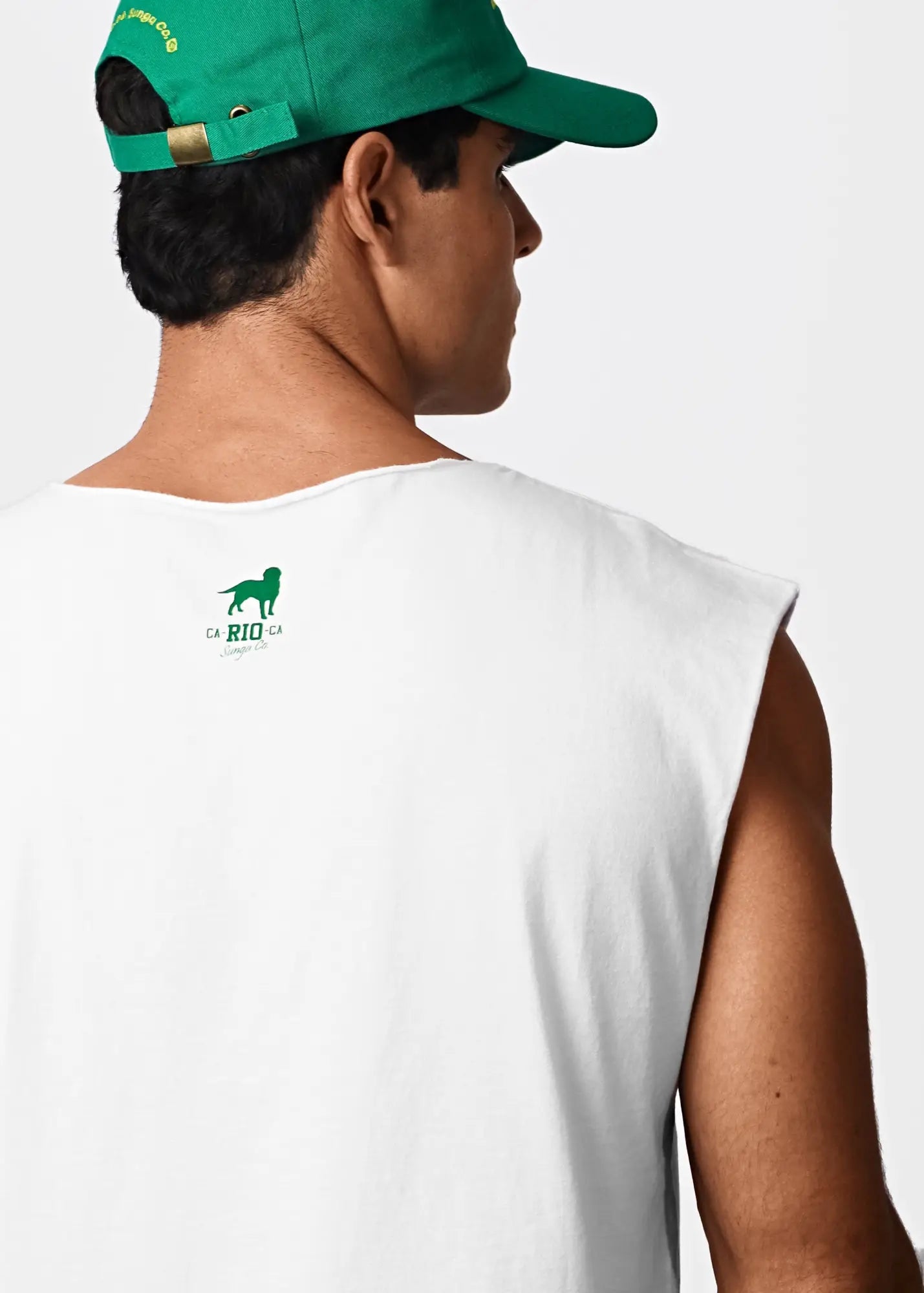 Back view of a white sleeveless cotton t-shirt with a green dog logo and da rio ca text, worn with a matching green cap