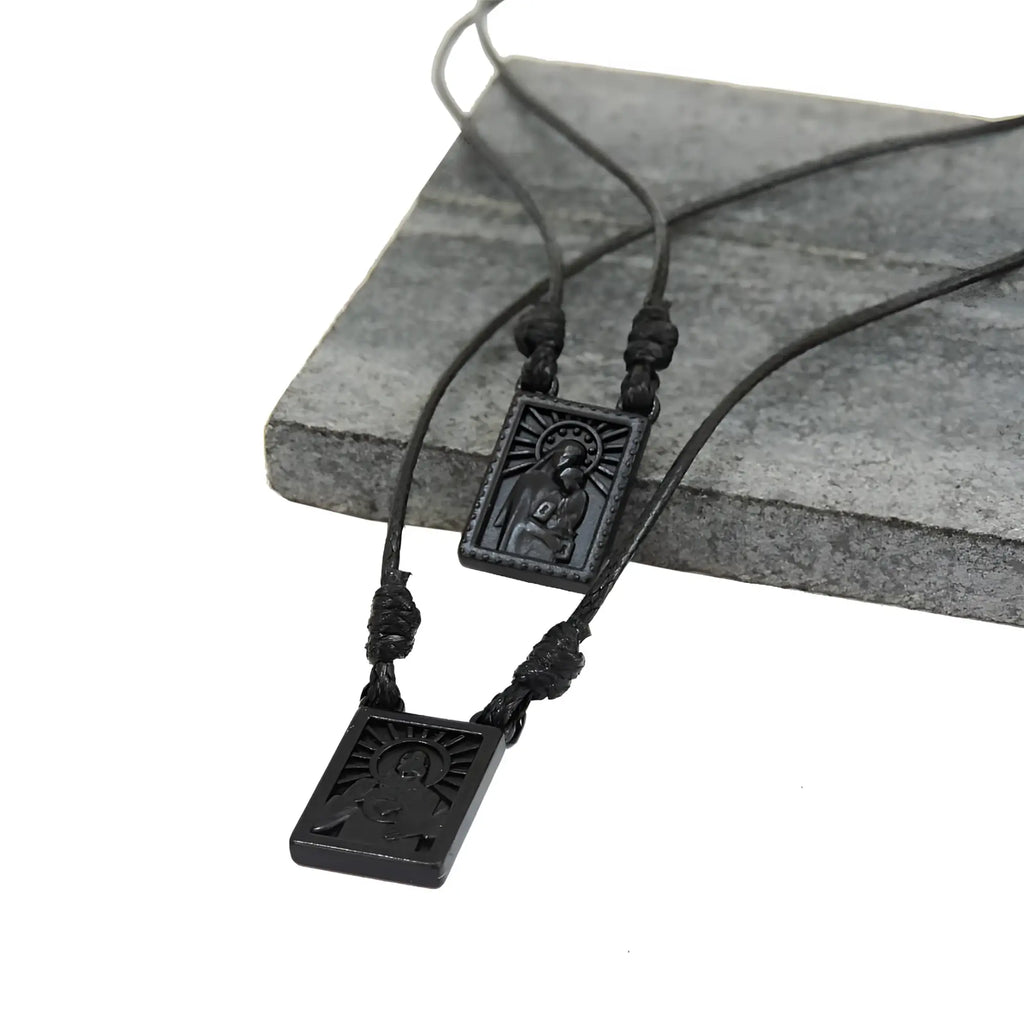 Male scapular necklace with black rectangular pendant engraved with religious figure and sunburst design matte finish