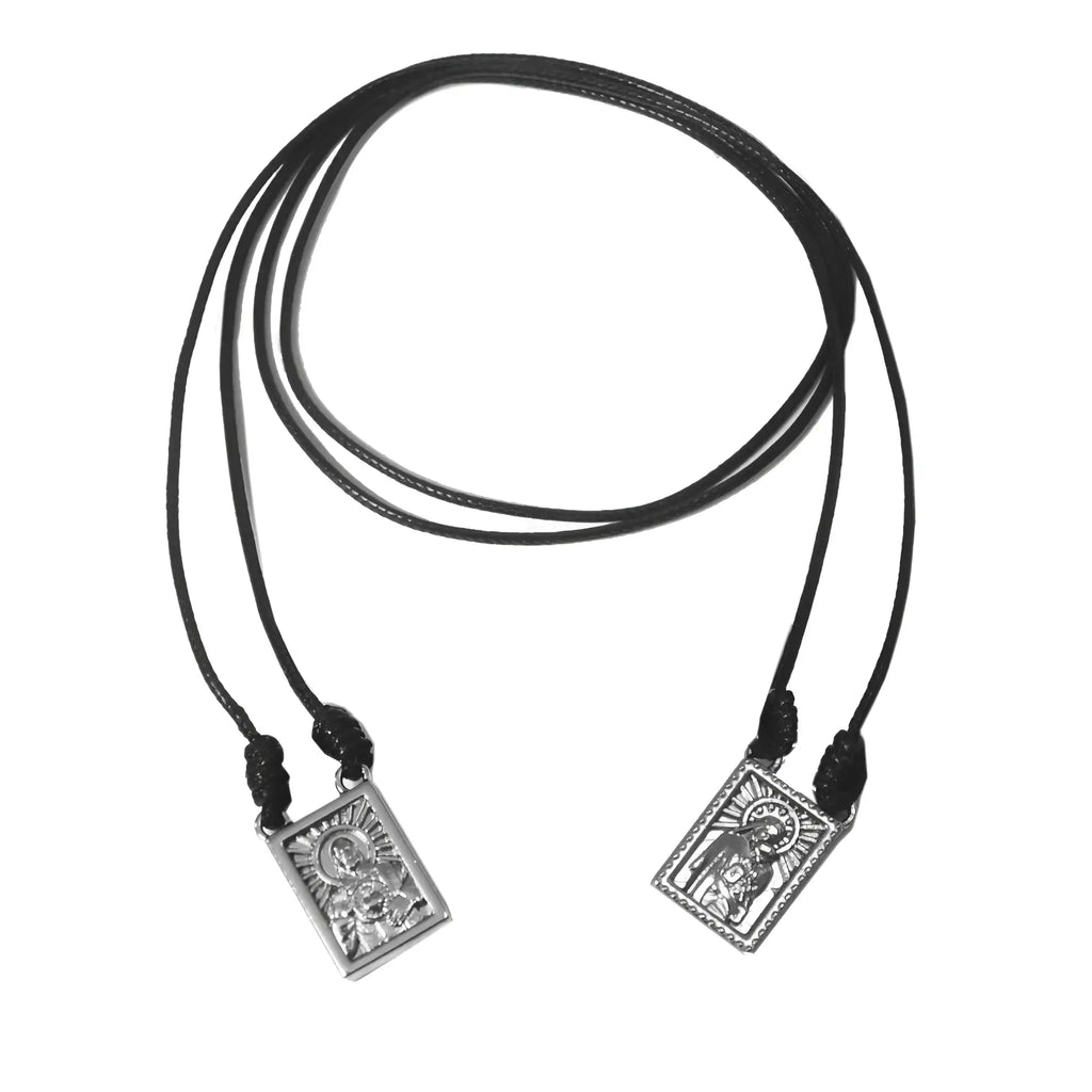 Black cord male scapular necklace with two silver-toned rectangular religious medallions and engraved halos