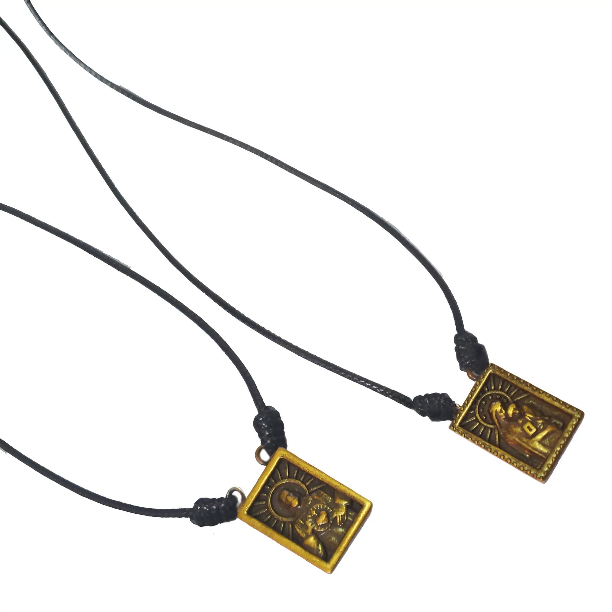 Two black cord male scapular necklaces with rectangular gold-toned metal pendants featuring embossed religious figures