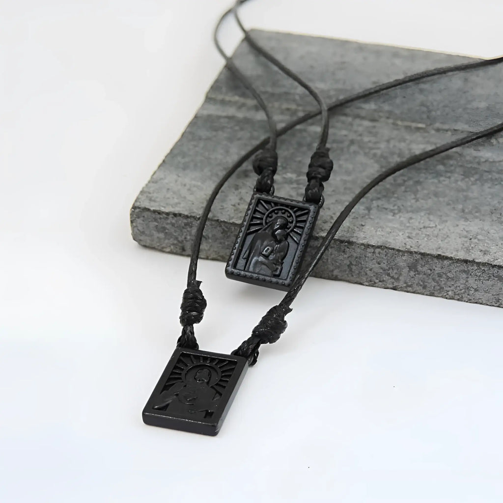 Male scapular with black rectangular pendant featuring engraved religious figure and sunburst design with matte finish