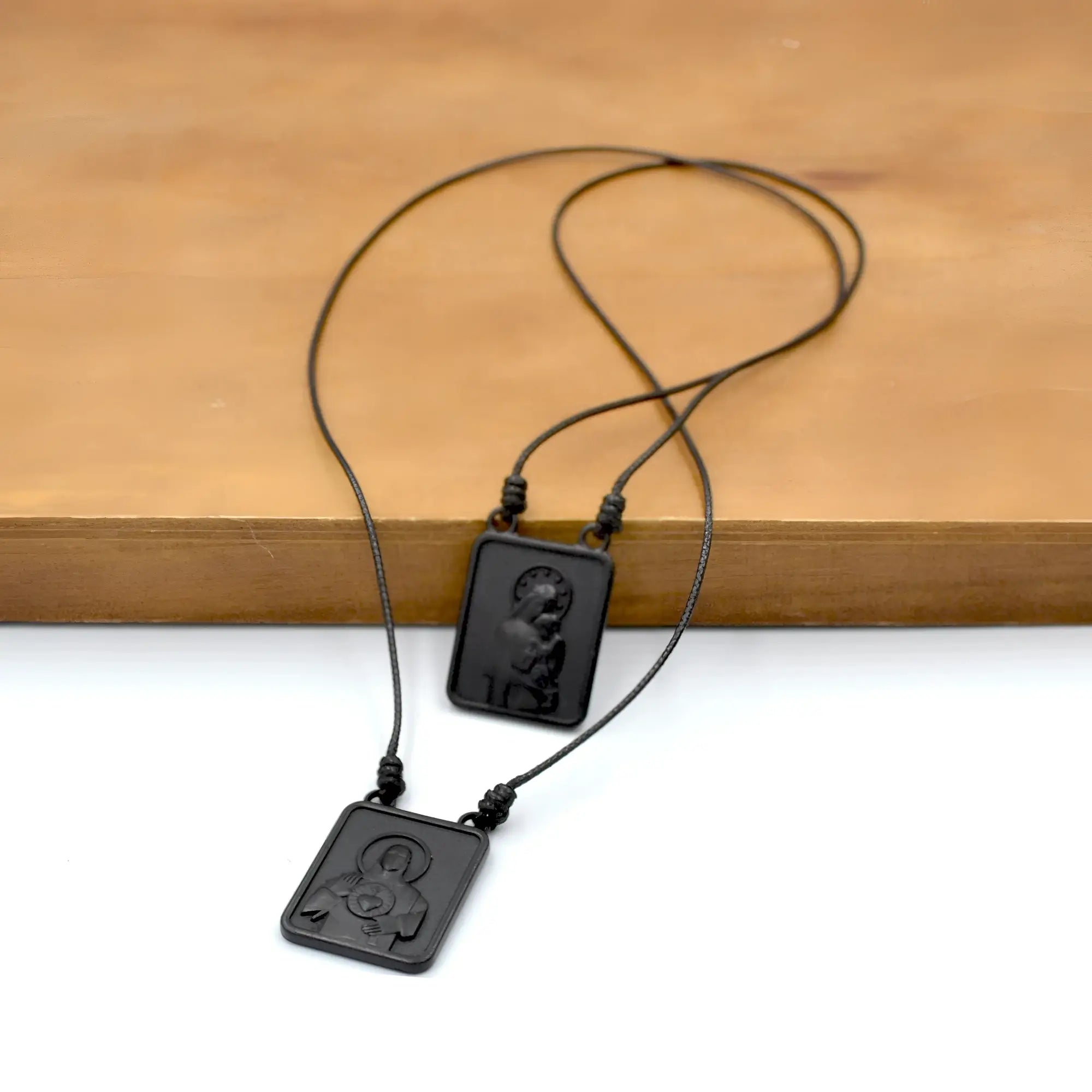 Black rectangular male scapular pendant necklace with engraved religious figure design and cord in pendant black