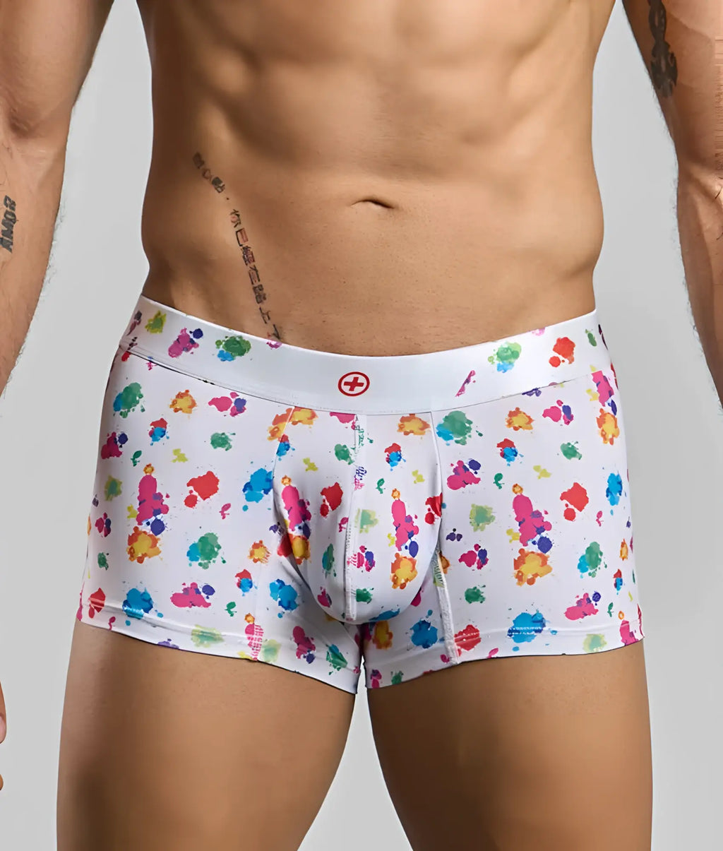 White boxer briefs with vibrant multicolored paint splatter pattern and red cross logo on waistband malebasics trunk hipster white splash