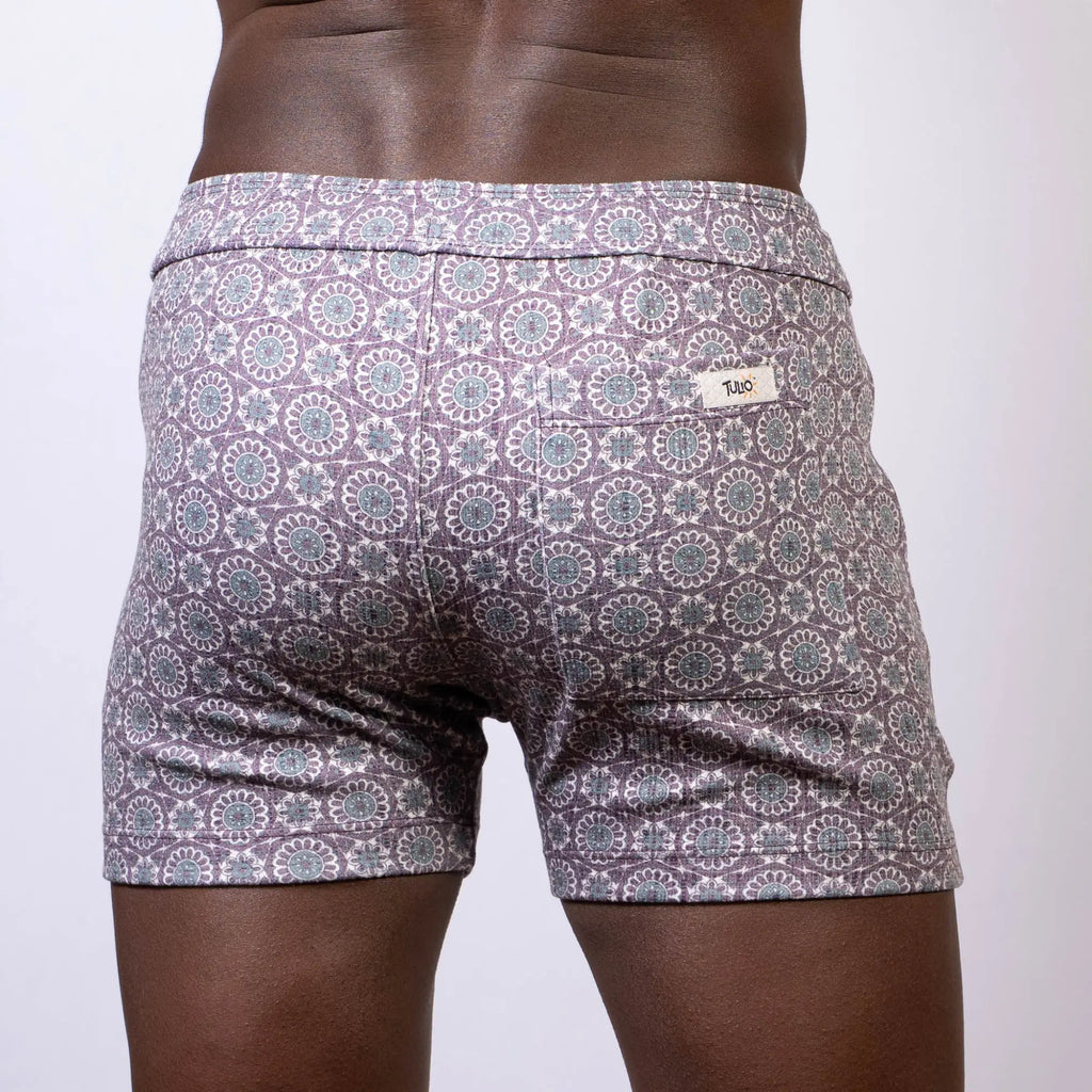 Back side of gray and white mandala linen texture shorts with a repeating circular pattern and a small brand tag