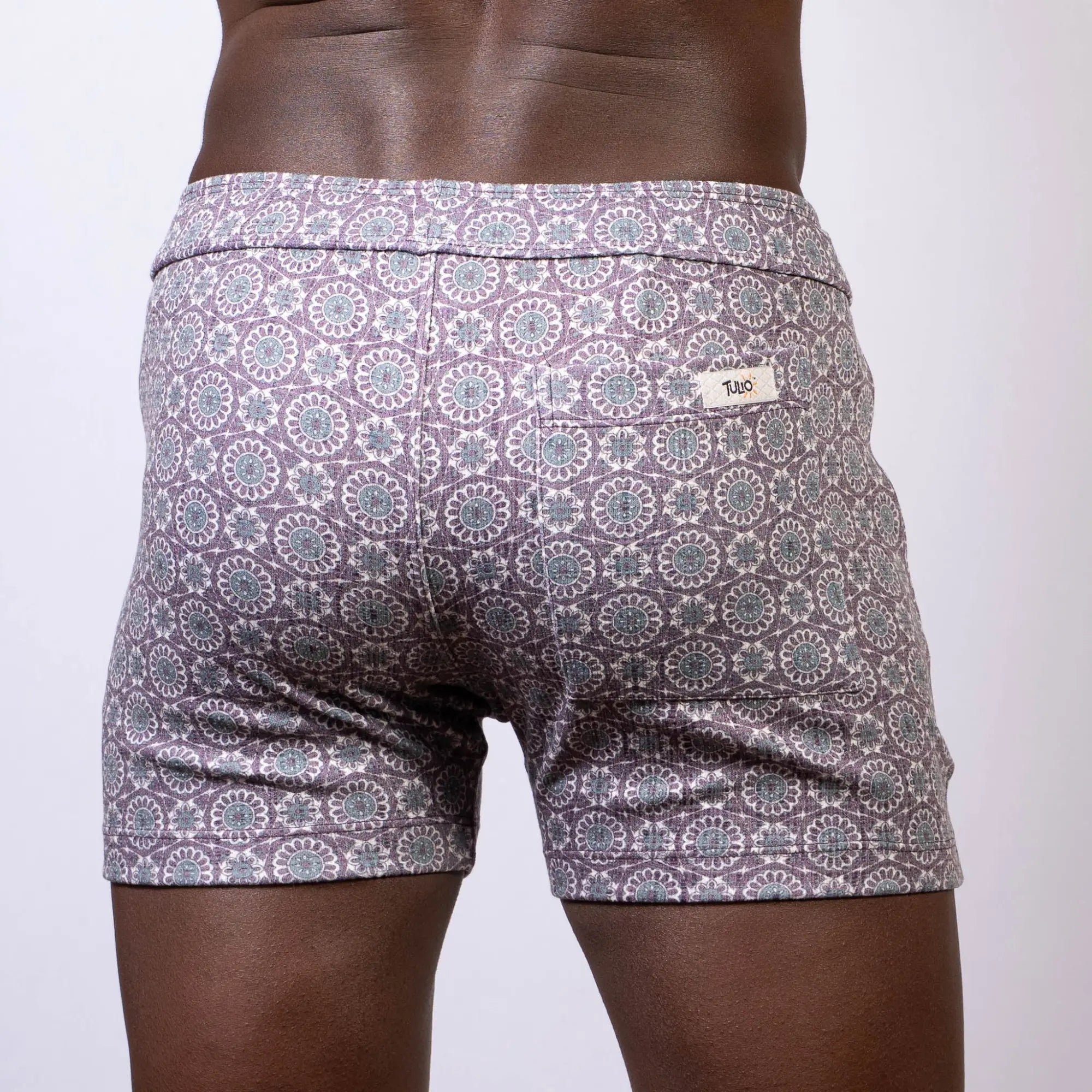 Back side of gray and white mandala linen texture shorts with a repeating circular pattern and a small brand tag