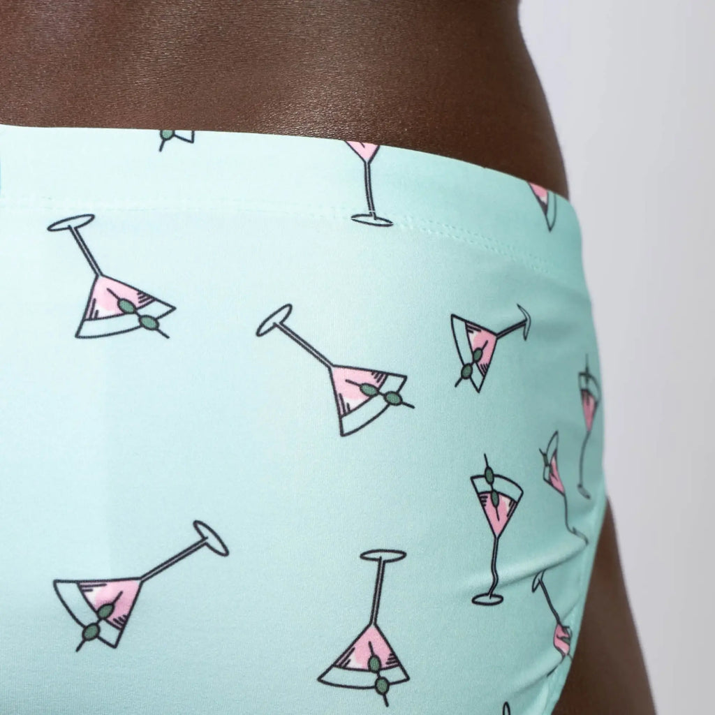 Mint green martini swim brief with pink martini glass pattern and olive garnish designed for swimming