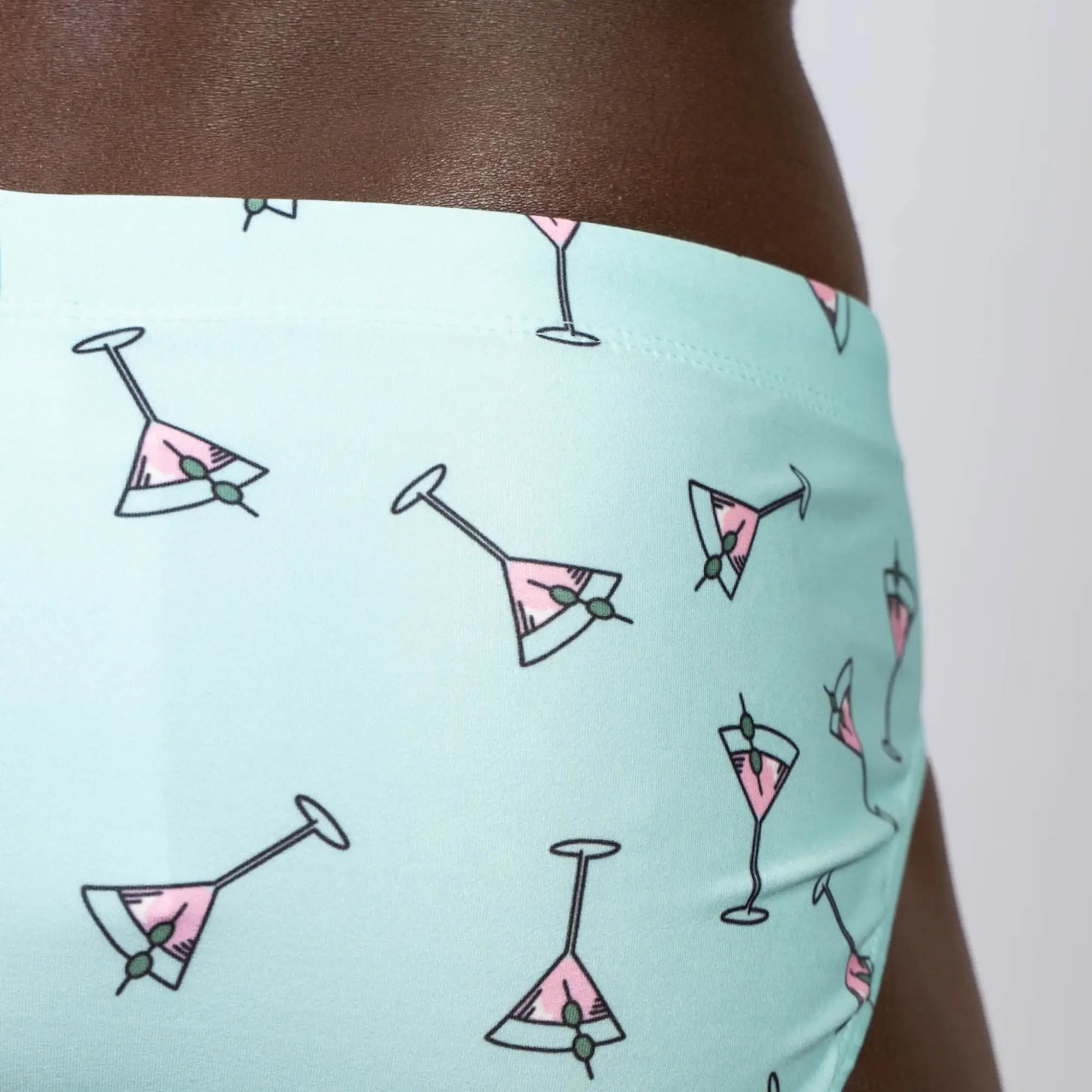 Mint green martini swim brief with pink martini glass pattern and olive garnish designed for swimming