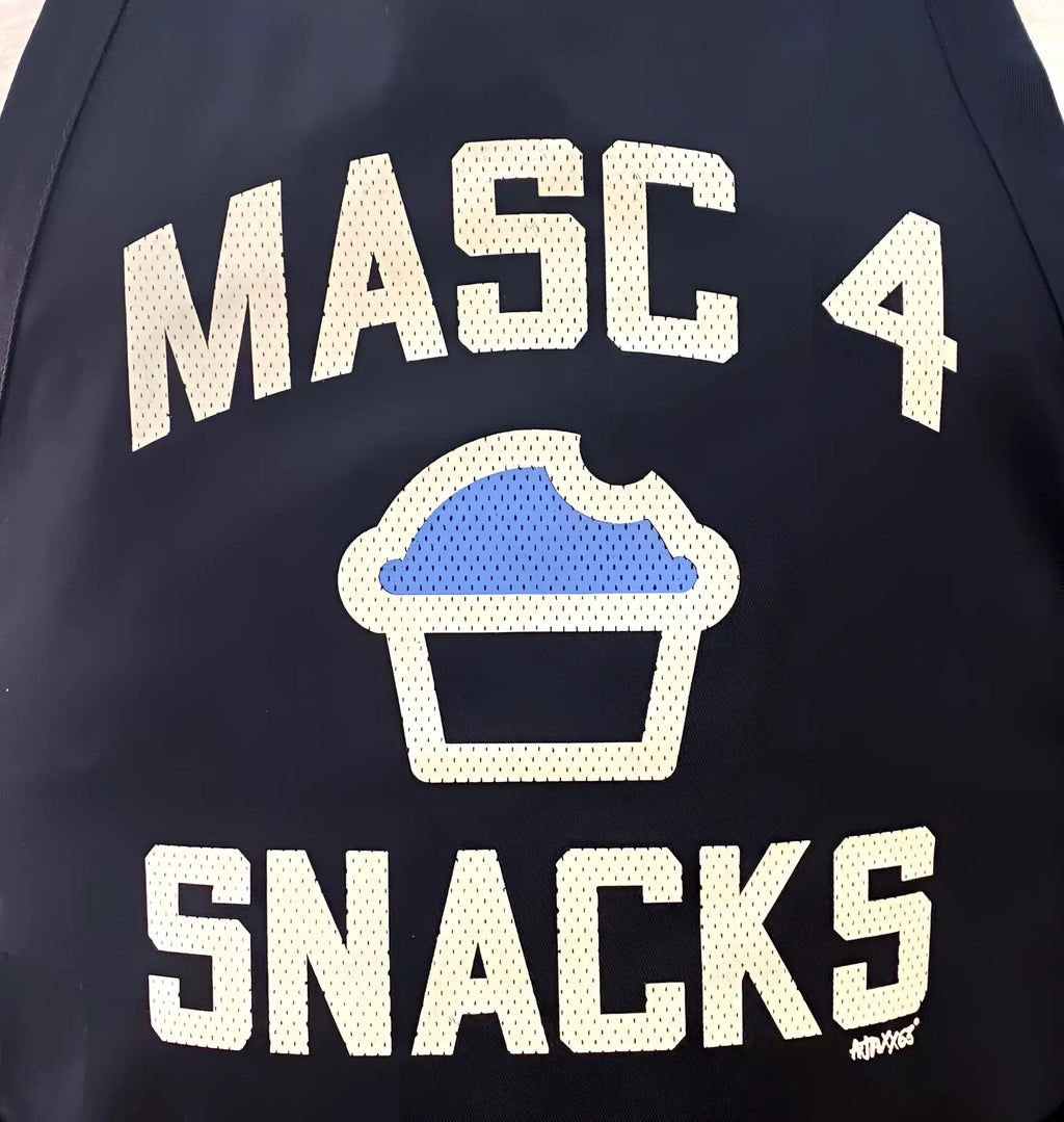 Dark navy bomber jacket with white mesh lettering and a blue cupcake graphic from masc4snacks apron collection