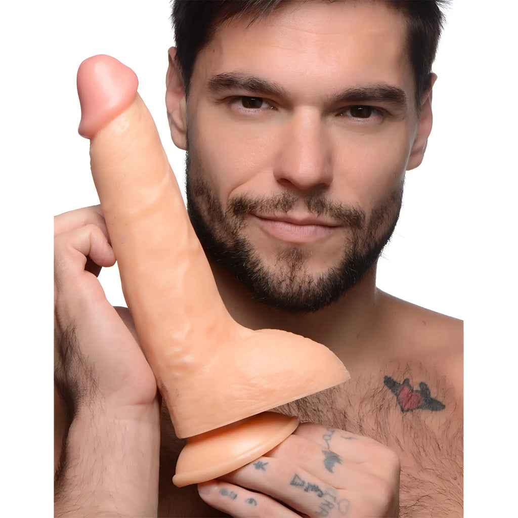 A man with a beard holds a 9-inch skin-toned Master Cock Beefy Brad dildo featuring a base and realistic detailing.