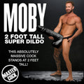 Master Cock Black Moby: A man displays a massive 2-foot tall black, textured super dildo in a black background studio.