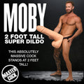 A muscular man holding a massive, 2-foot-tall, skin-toned Moby Huge super dildo against a black background.
