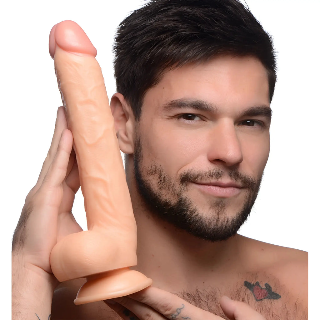 A man holding a 10-inch, skin-tone Master Cock Long Logan dildo with detailed texture and a base.
