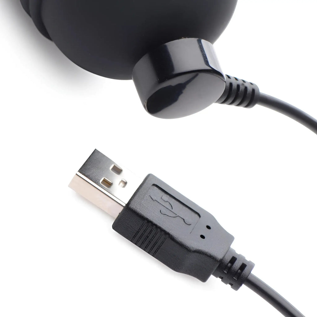 Master Series 10X dildo: close-up of the black magnetic charging port connected to a USB cable against a white background.