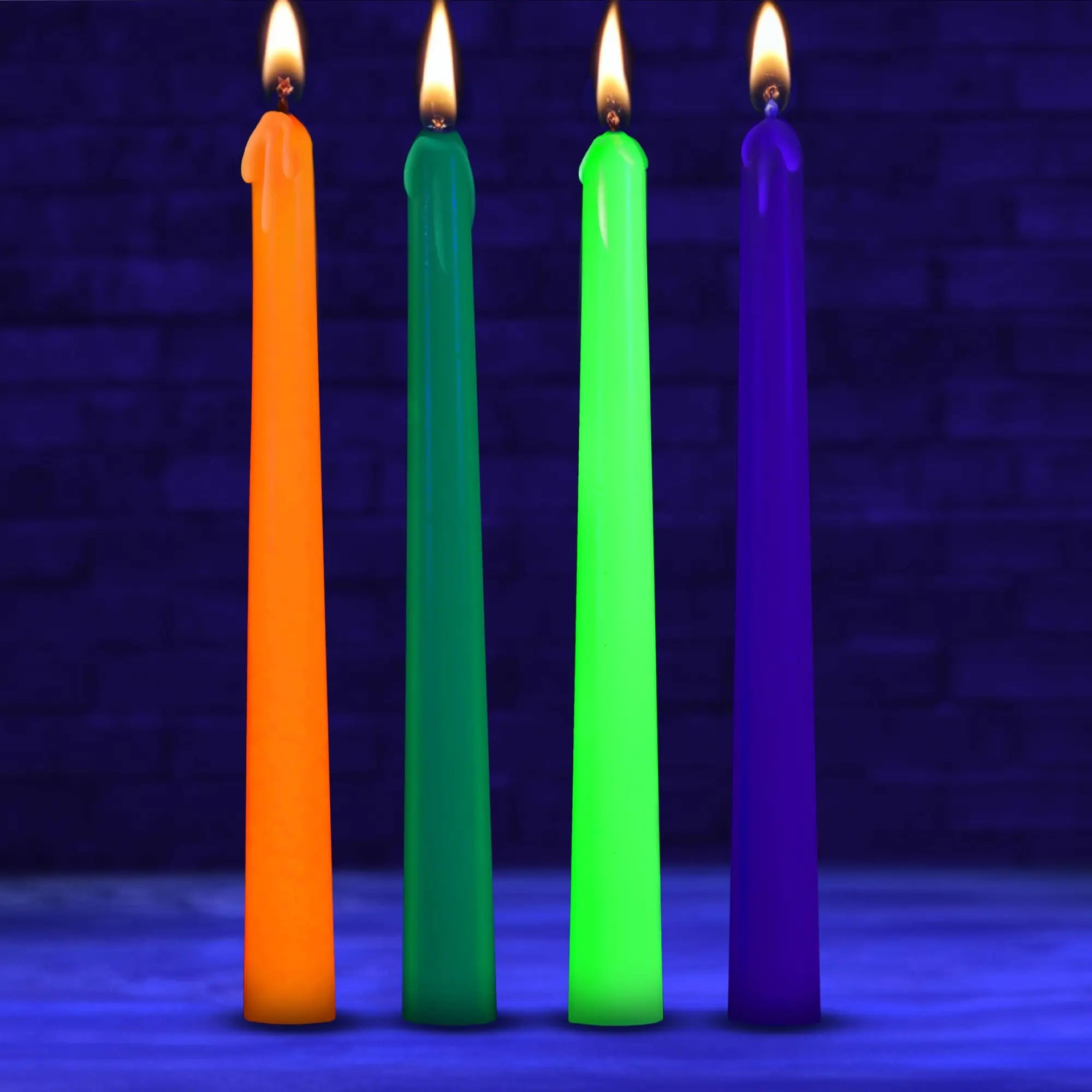 Four Master Series UV glow taper candles in orange, green, neon yellow, and purple, all lit against a dark background.