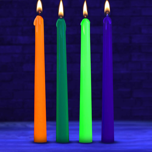 Four Master Series UV glow taper candles in orange, green, neon yellow, and purple, all lit against a dark background.