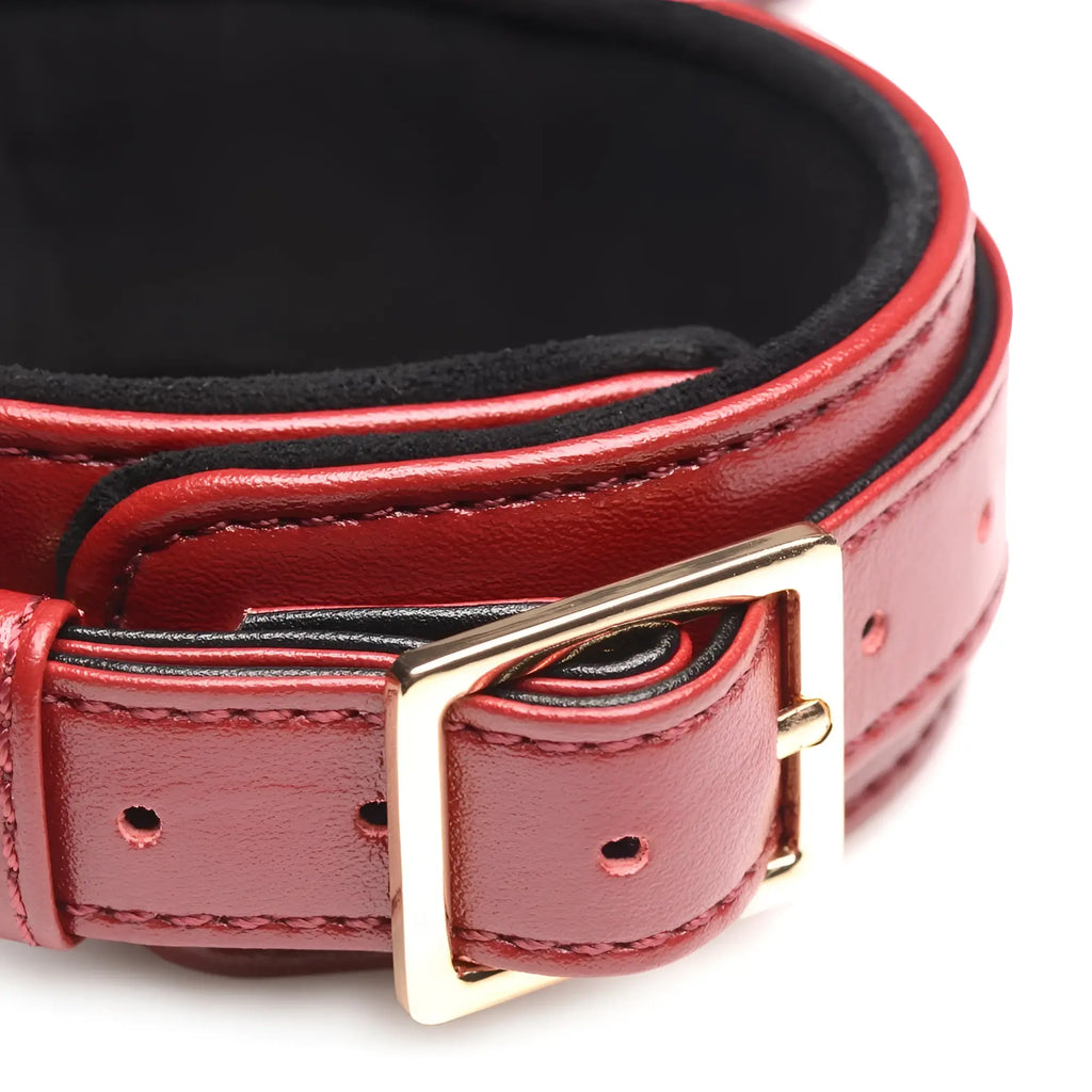 Master Series Burgundy Bondage Set: Close-up of a deep red faux leather cuff with black lining and gold-tone buckle.
