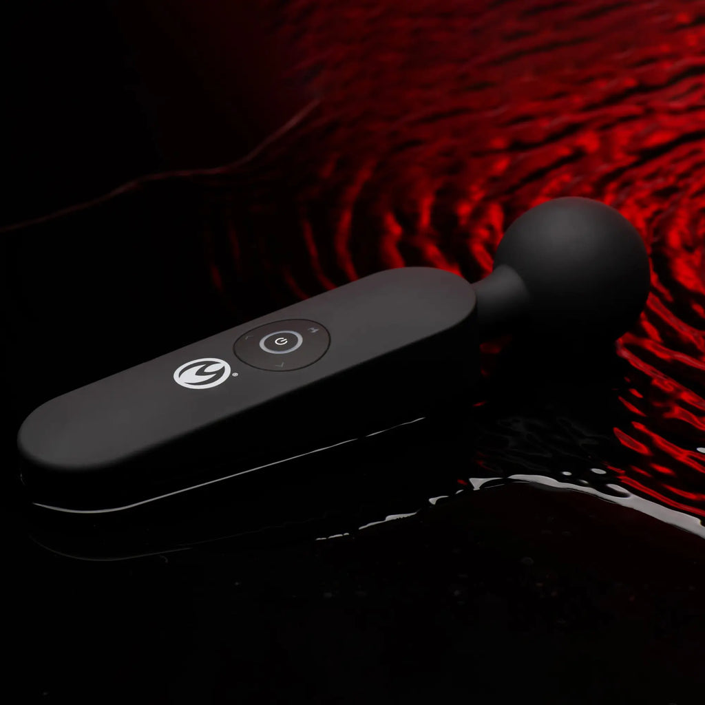 Master Series 72X silicone heating wand massager in matte black, featuring a round head, resting on rippling red water.