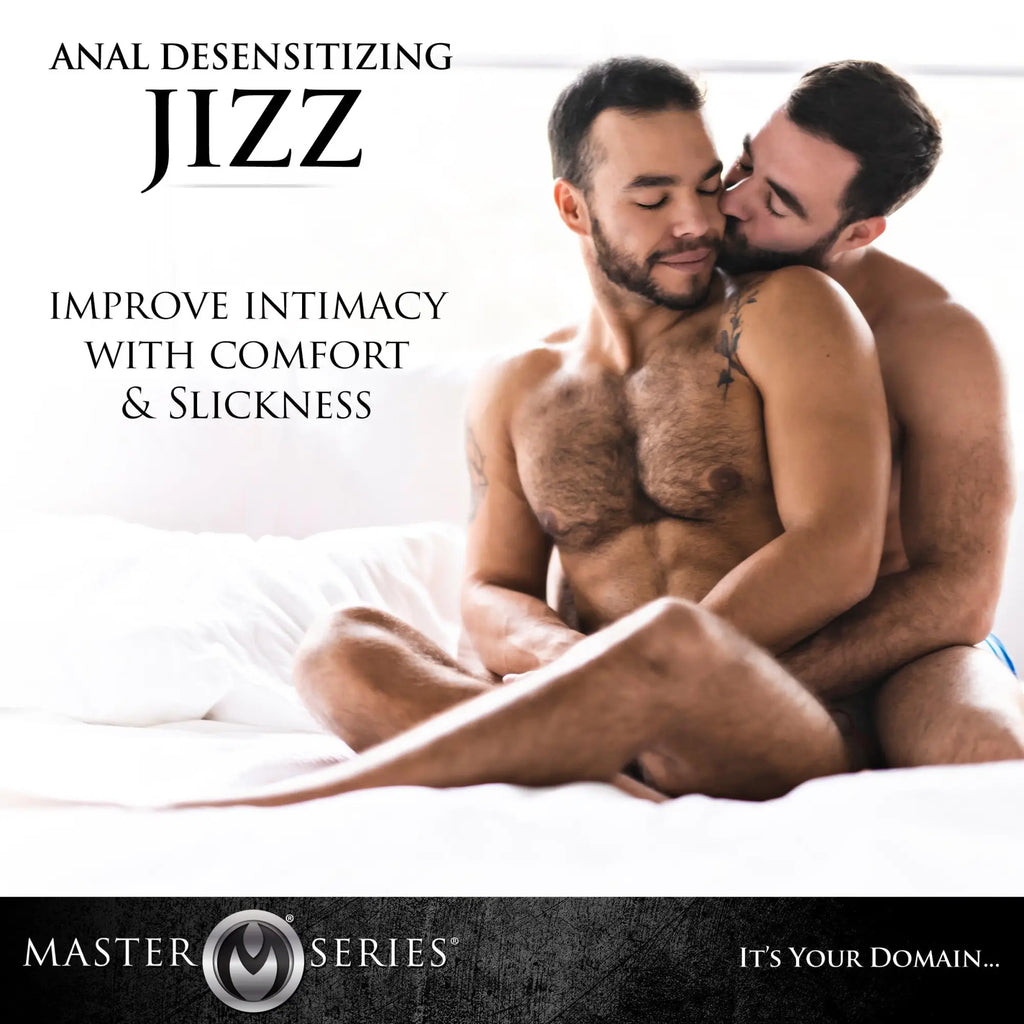 Two shirtless men cuddling on a bed. Text advertises Master Series 8.5oz Jizz Scented Desensitizing Lube.