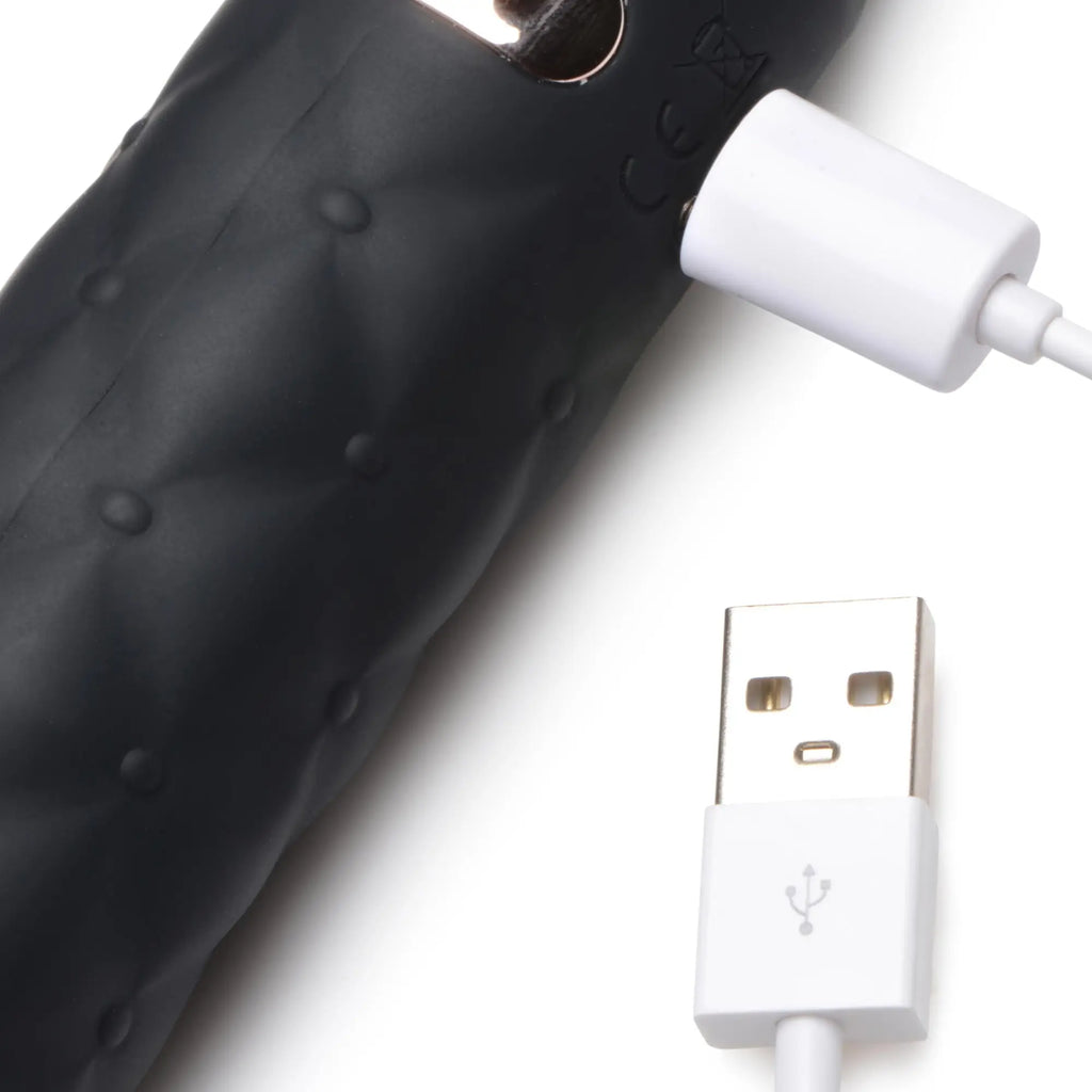 Master Series 9X Vibrating Silicone Dildo Flogger shown in black with a white USB magnetic charging cable.