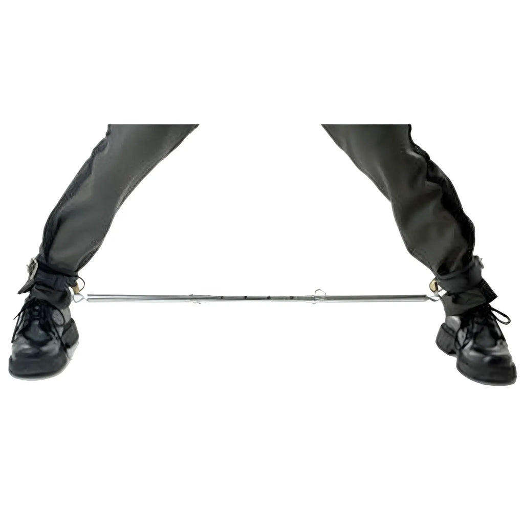 Master Series Adjustable Steel Spreader Bar connecting the ankles of a person wearing black leather pants and boots.