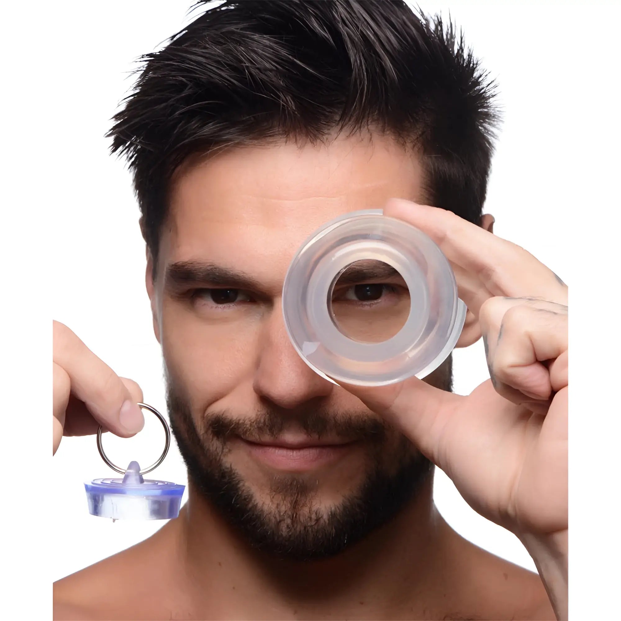 A man holds the clear, hollow Master Series Ass Bung dilator over his eye and the matching plug in his other hand.