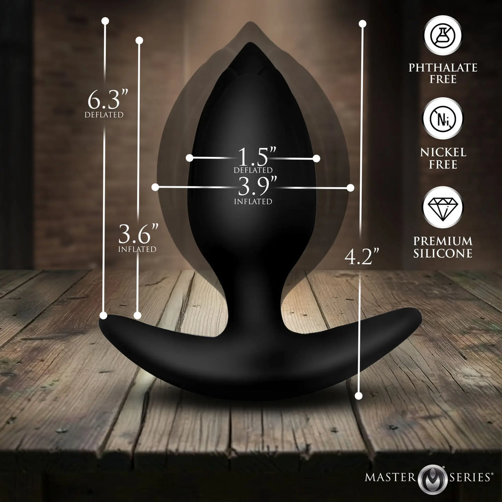 Master Series black silicone inflatable anal plug showing size dimensions in deflated and inflated states on wood table.