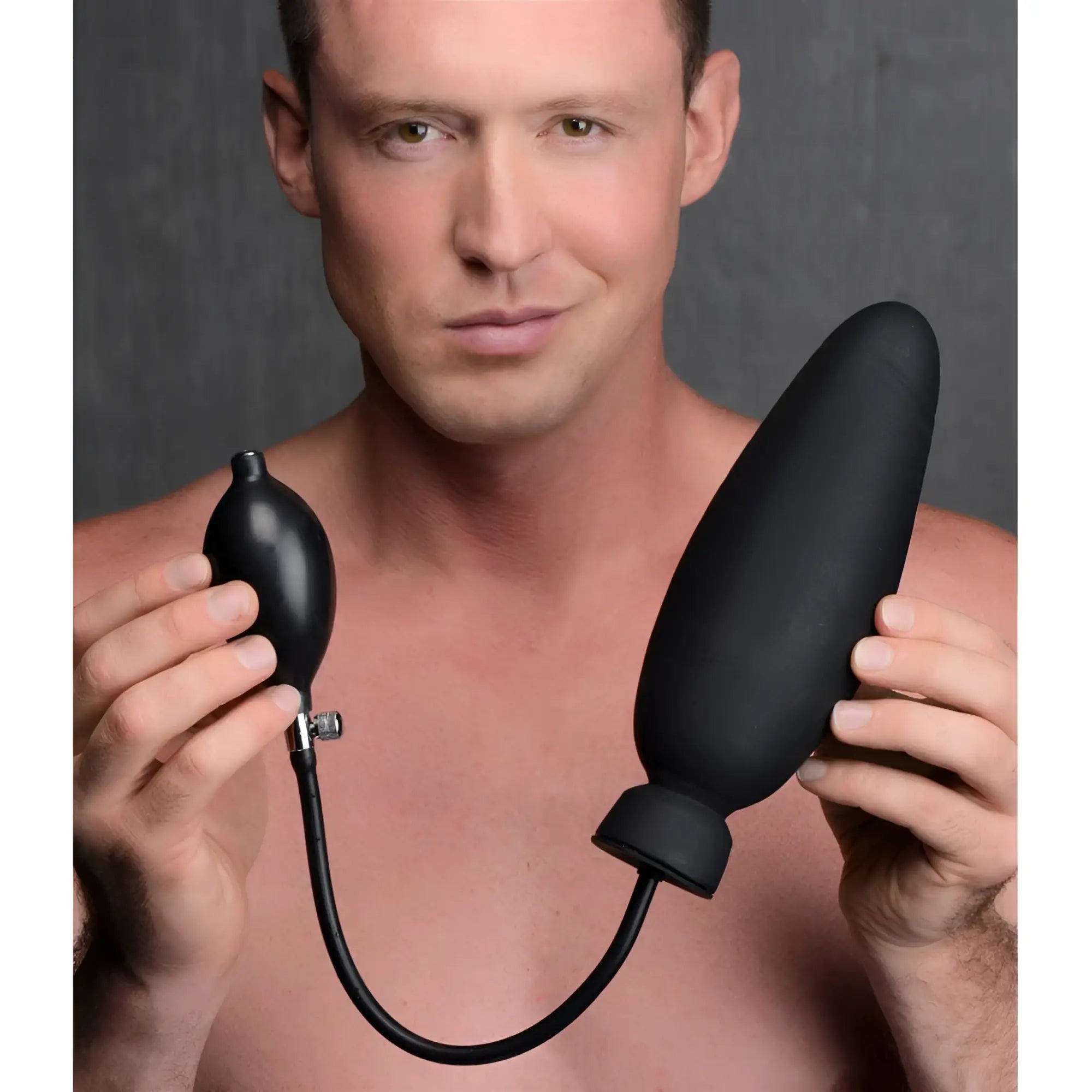 A man holds a black Master Series Ass-Pand inflatable silicone dildo, featuring a hand pump and bulb.