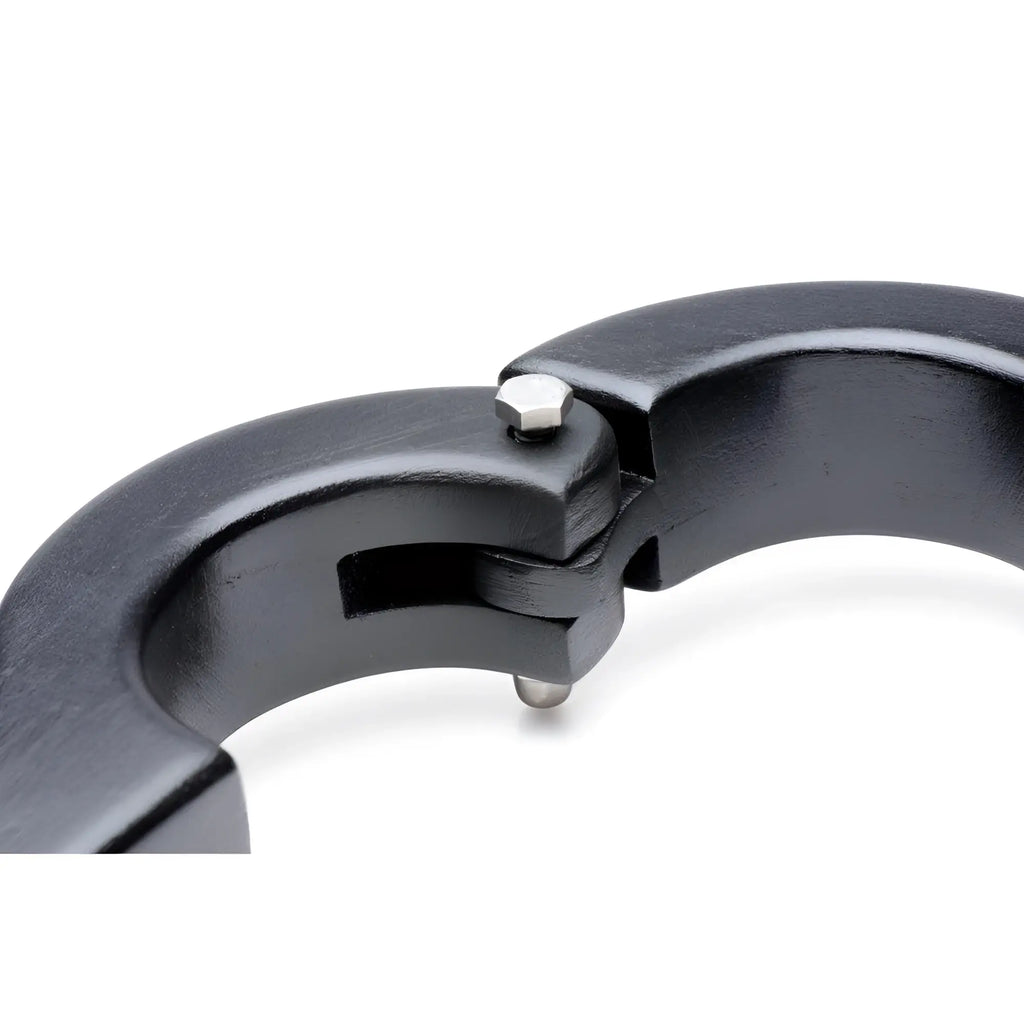 Master Series Balls to Wrist Humbler: A close-up of a black, curved metal restraint with a silver hinge and bolt.