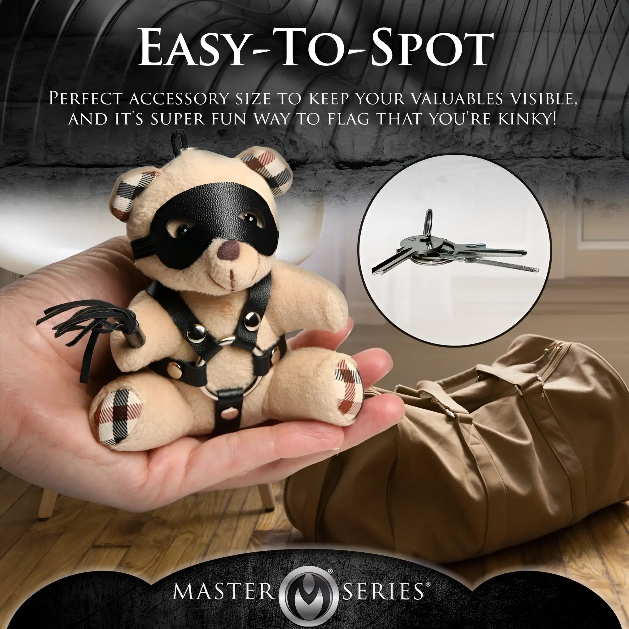 Master Series BDSM teddy bear keychain: tan plush bear with black leather eye mask, harness, and miniature whip.